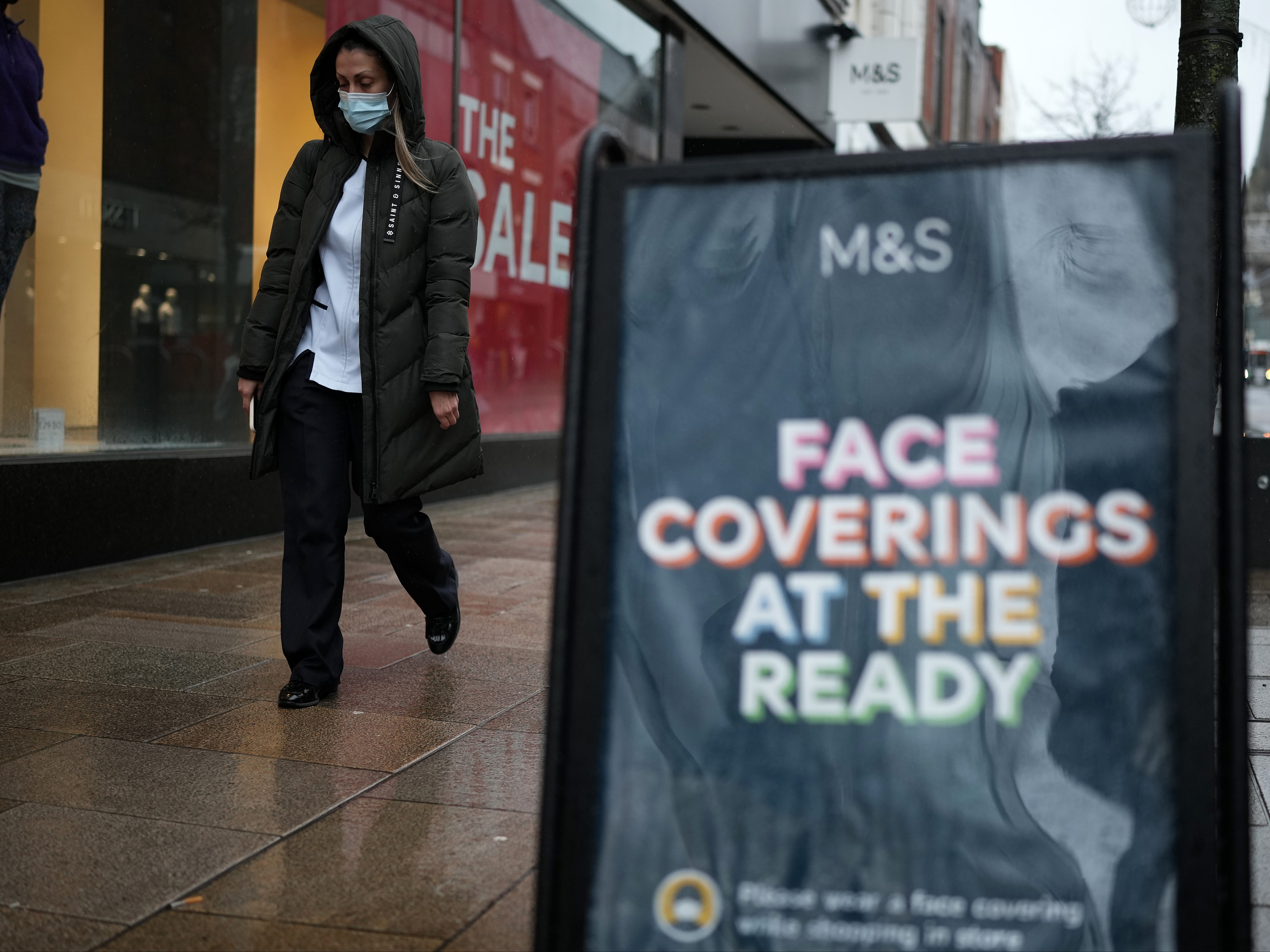 <p>People wear face masks as they shop in the rain in Preston </p>