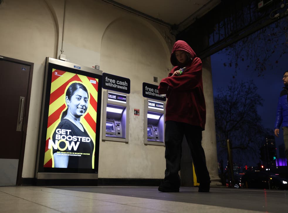 People walk through Embankment Station passing a get boosted advert (James Manning/PA)