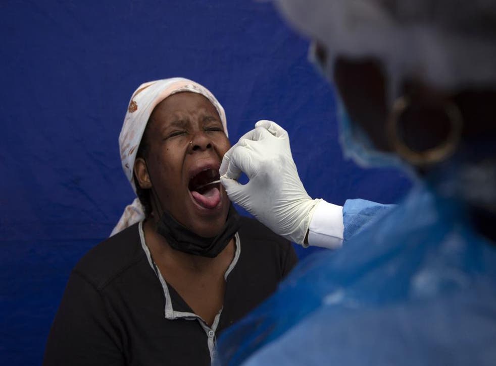 <p>A throat swab is taken from a patient to test for Covid at a facility in Soweto, South Africa</p>