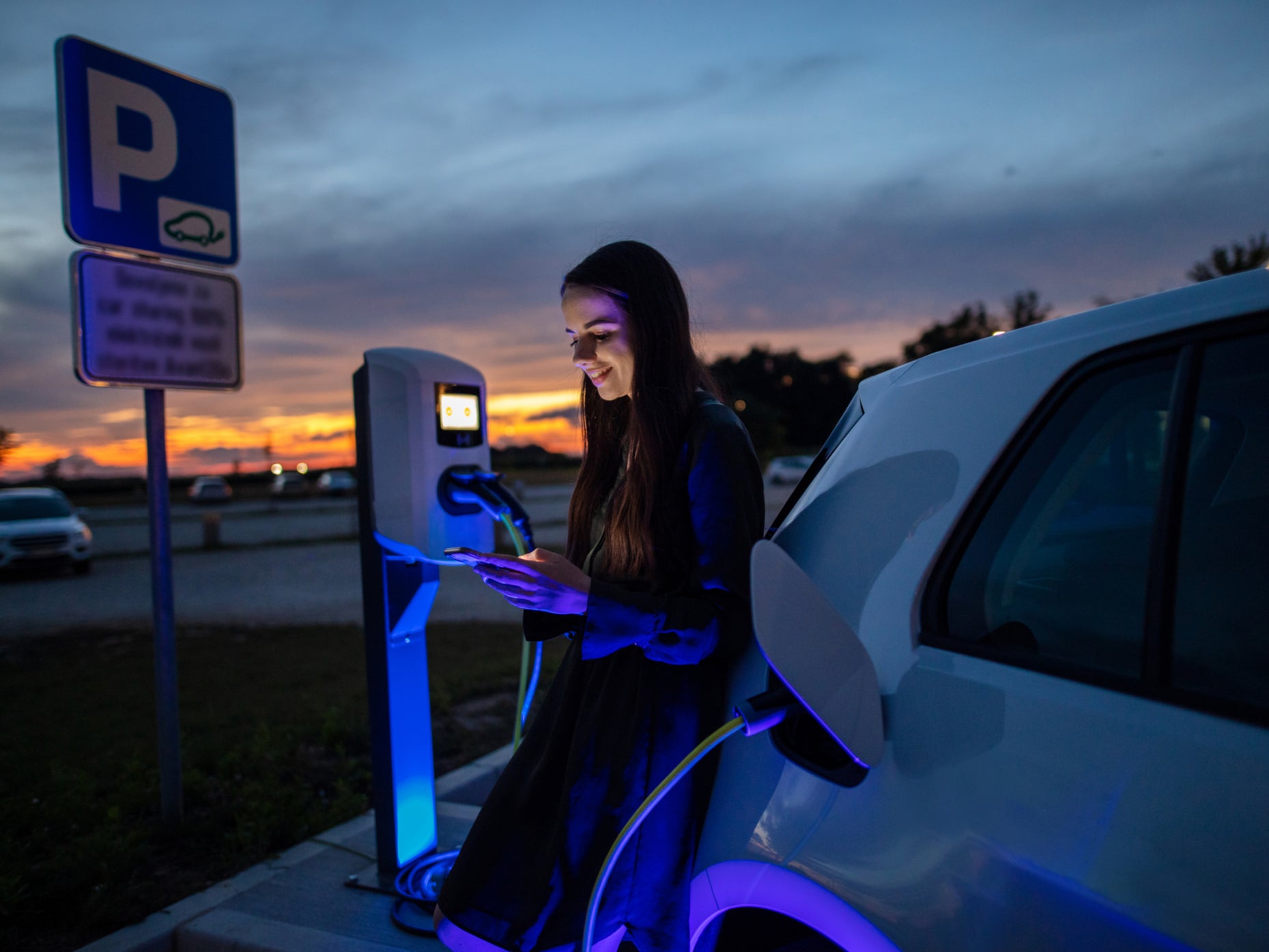 A woman charges her electric car