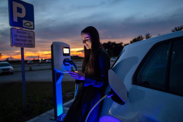 <p>A woman charges her electric car</p>