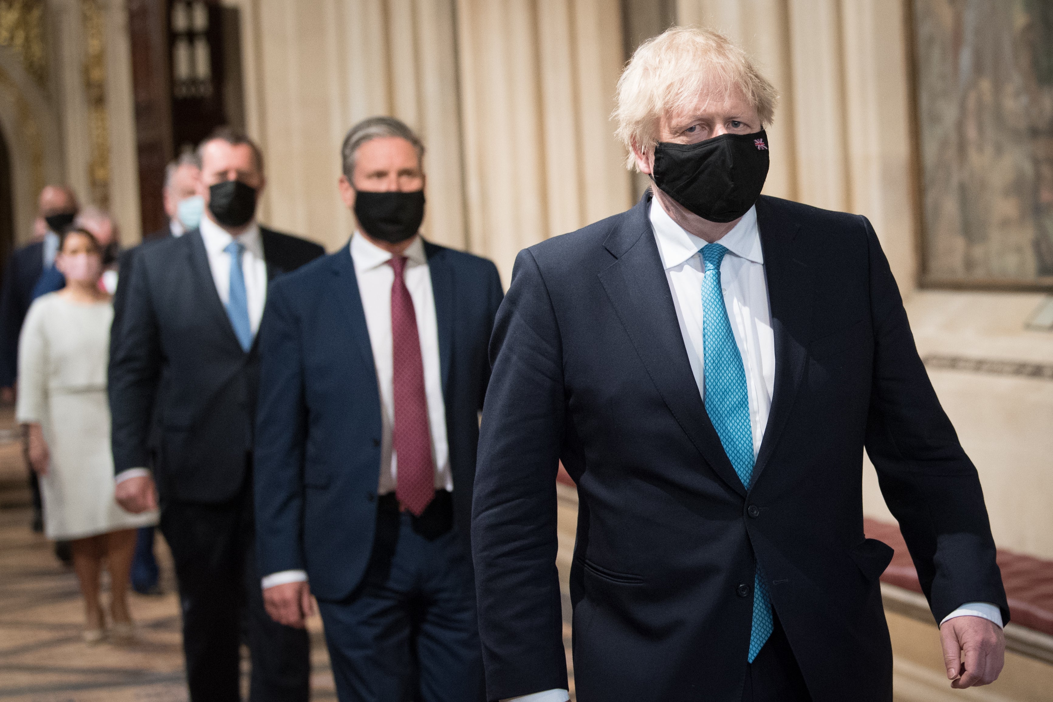 Prime Minister Boris Johnson with Labour leader Sir Keir Starmer behind him walk through the Central Lobby on their way from the House of Lords after listening to the Queen’s Speech (Stefan Rousseau/PA)