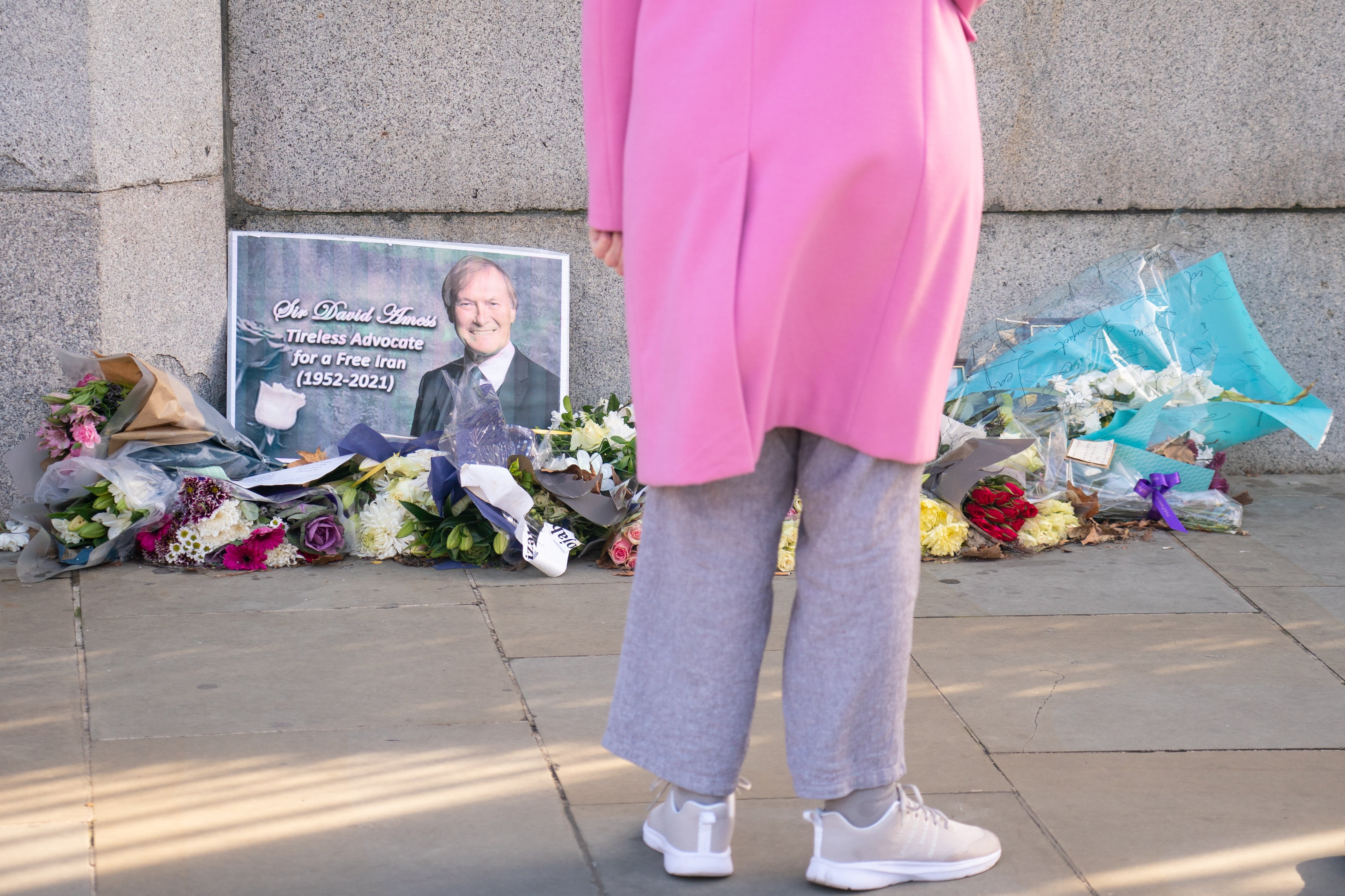 A person views flowers left in memory of Sir David Amess outside the Houses of Parliament (Dominic Lipinski/PA)
