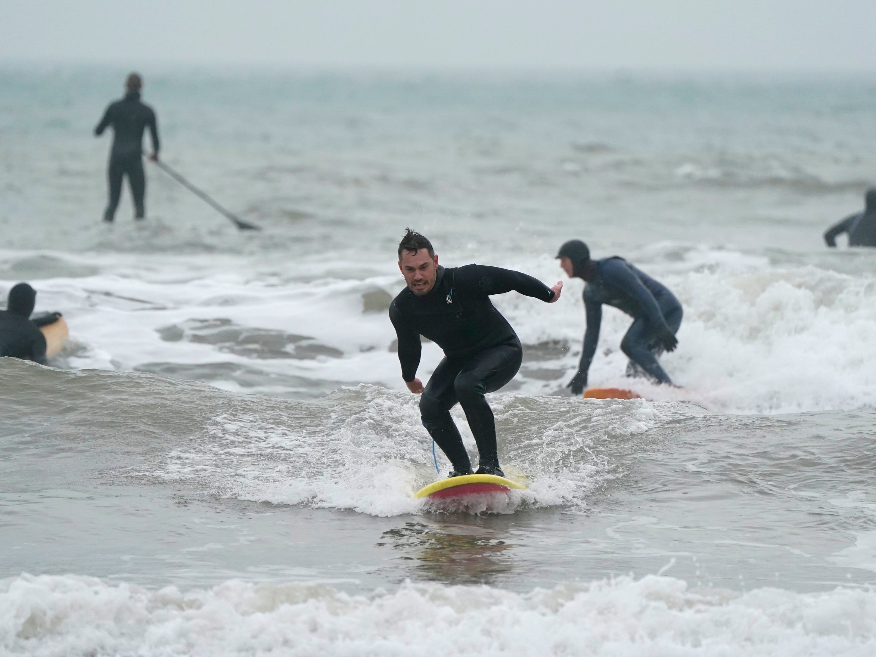 A surfer rides a wave in the sea off of Bournemouth beach in Dorset