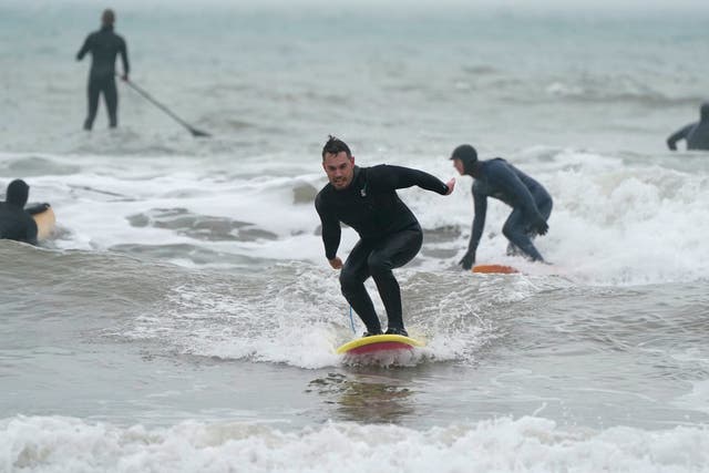 <p>A surfer rides a wave in the sea off of Bournemouth beach in Dorset</p>