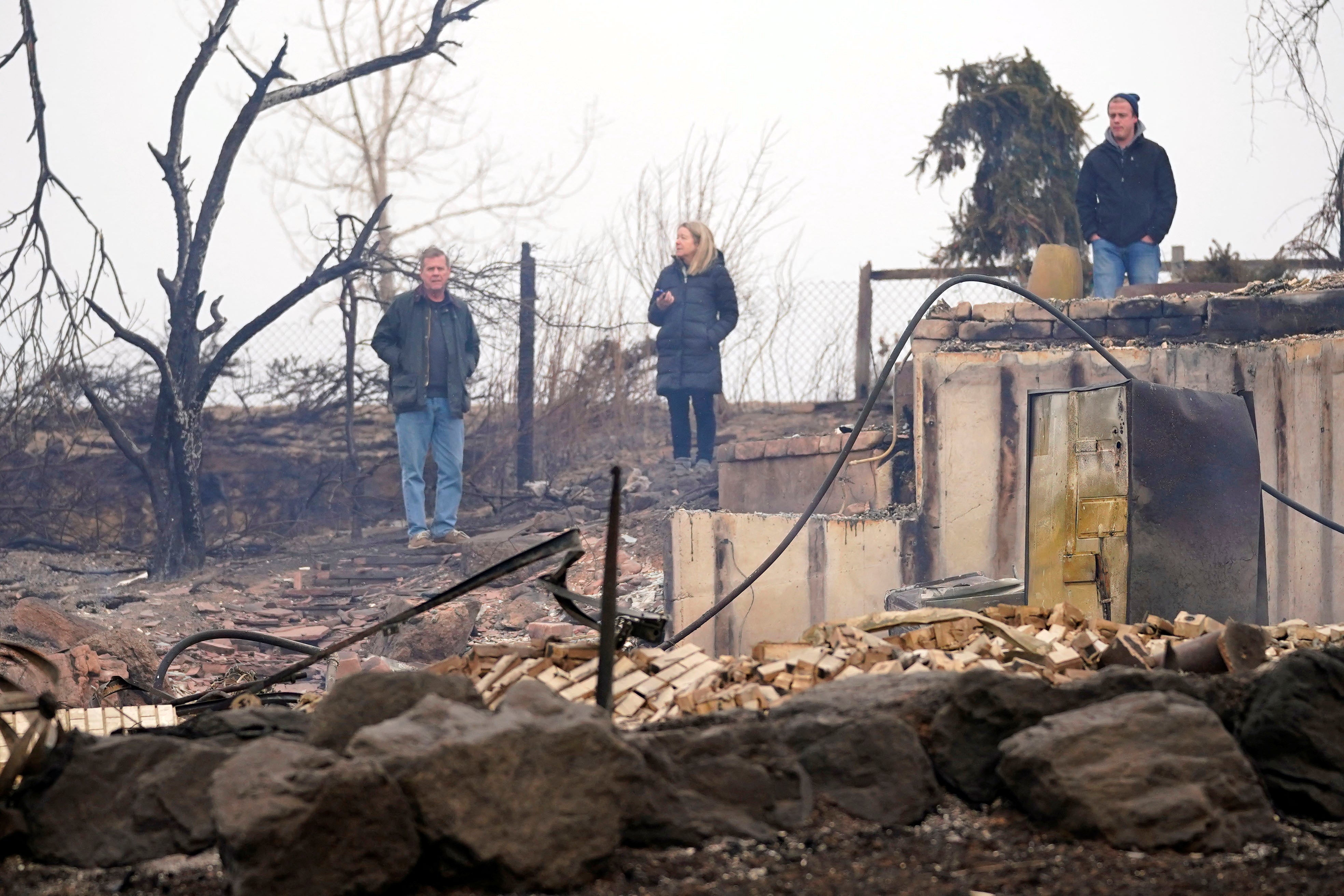 Frank, Deb, and Christian Harrison react to the the damage of their home in The Enclave after the wildfire in Louisville, Colorado