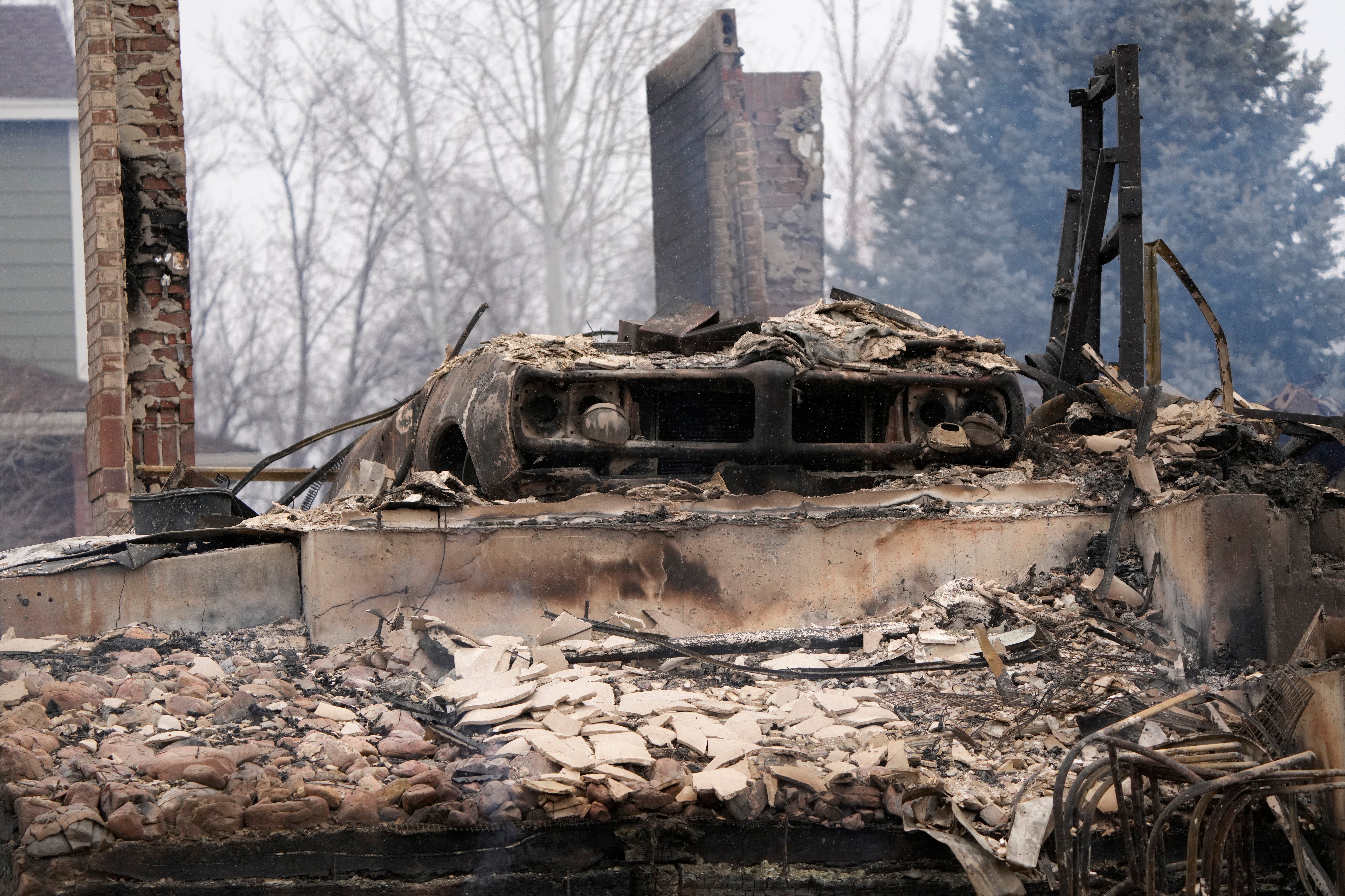 A charred vehicle sits amid the remains of homes burned by the wildfires after they ripped through a housing development