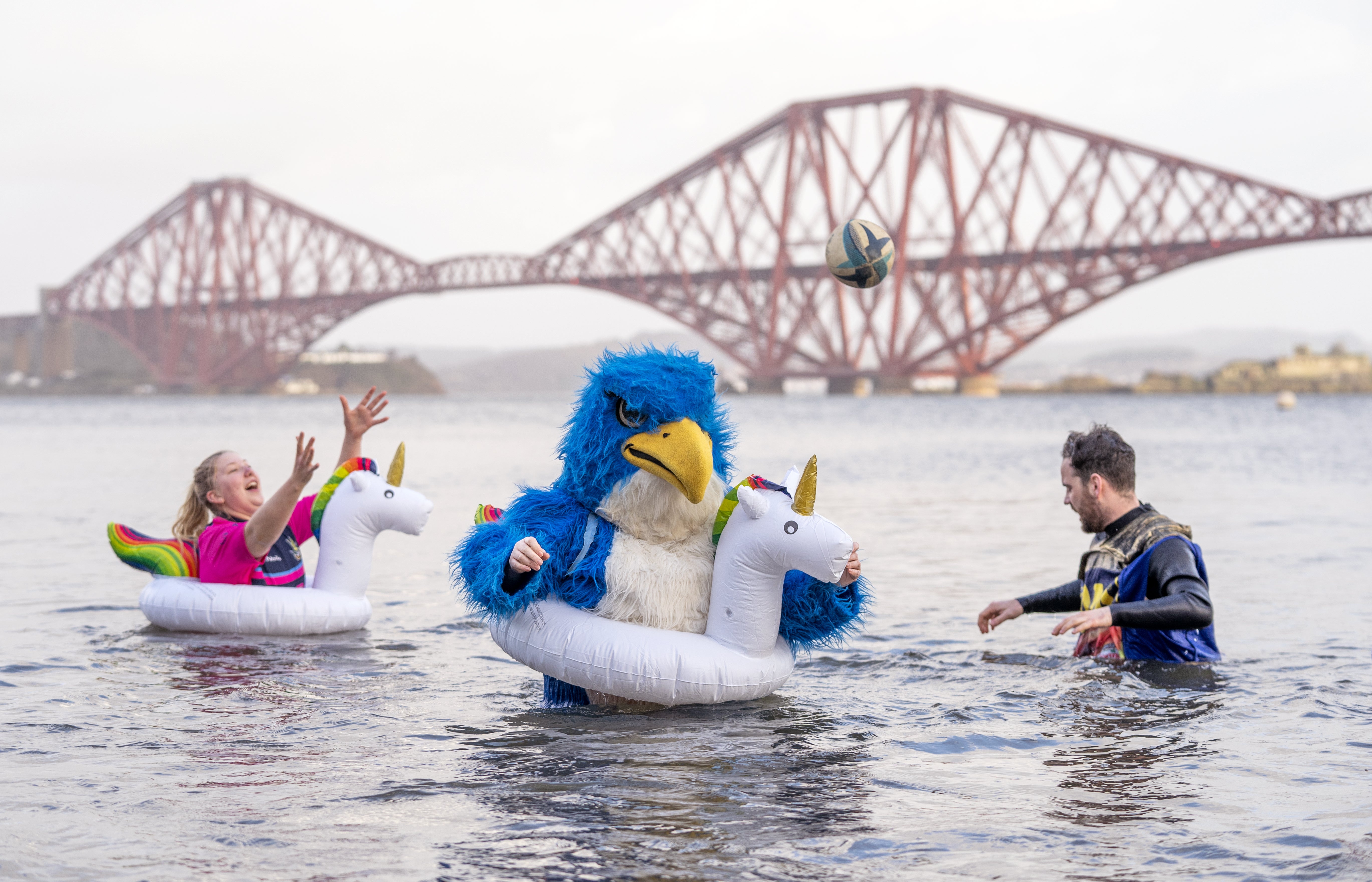People take part in a New Year’s Day dip in front of the Forth Bridge at South Queensferry, Edinburgh (Jane Barlow/PA)