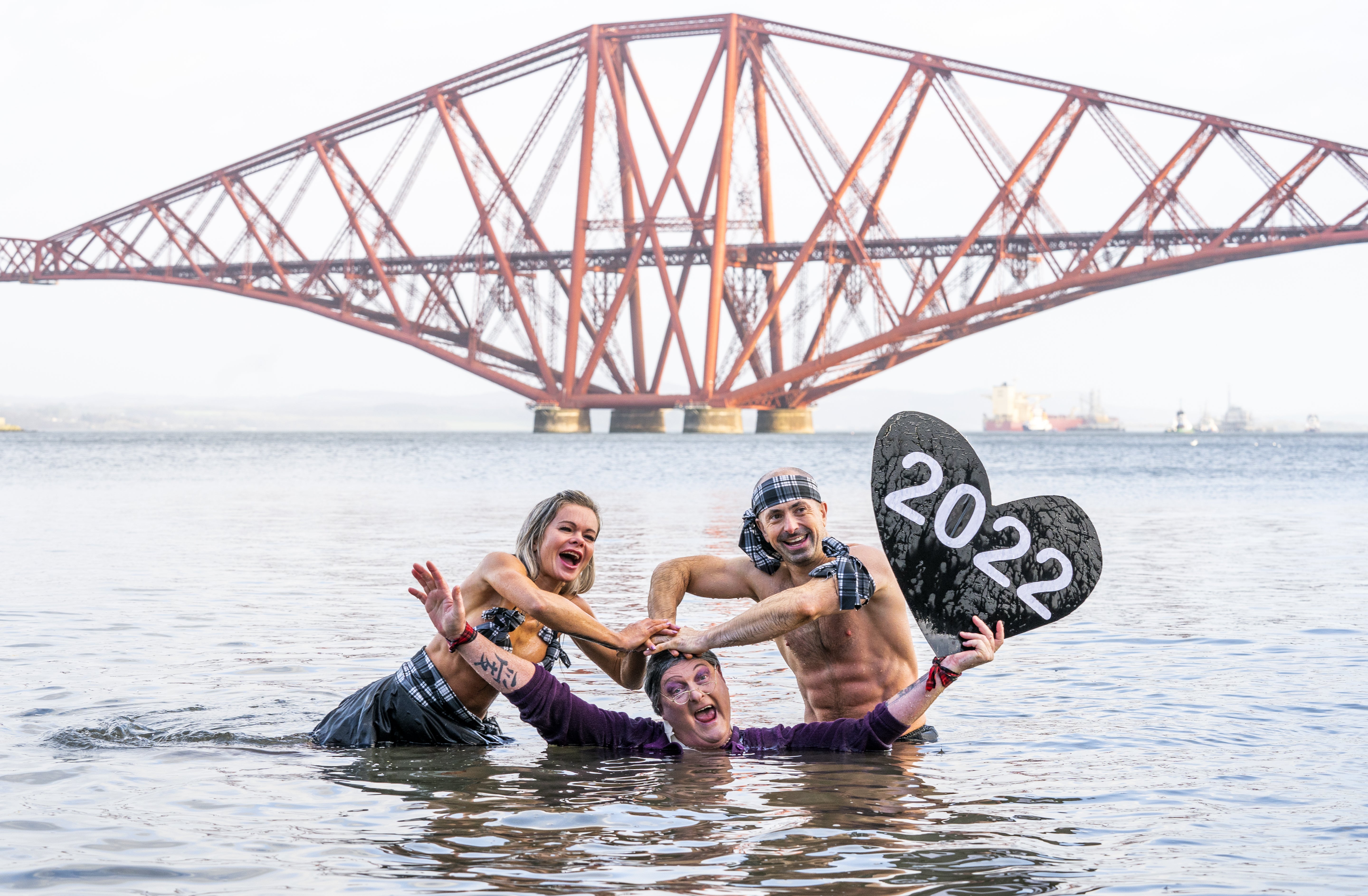 People take part in a New Year’s Day dip in front of the Forth Bridge at South Queensferry, Edinburgh (Jane Barlow/PA)