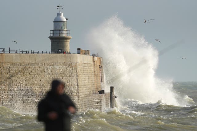 A fisherman on the beach in Folkestone, Kent, as waves crash against the harbour wall (Gareth Fuller/PA)