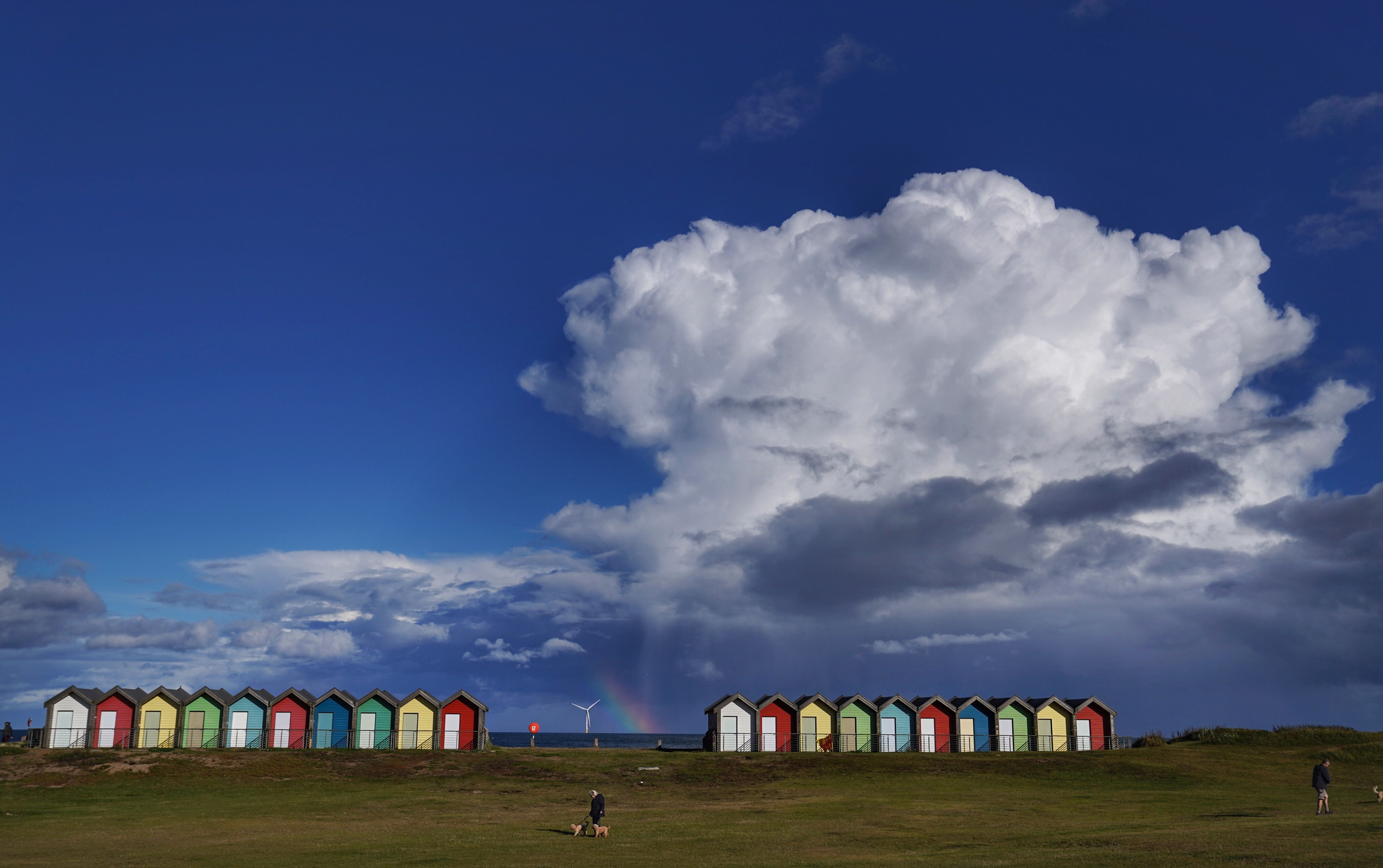 A rainbow appears behind the Blyth beach huts in Northumberland (Owen Humphreys/PA)