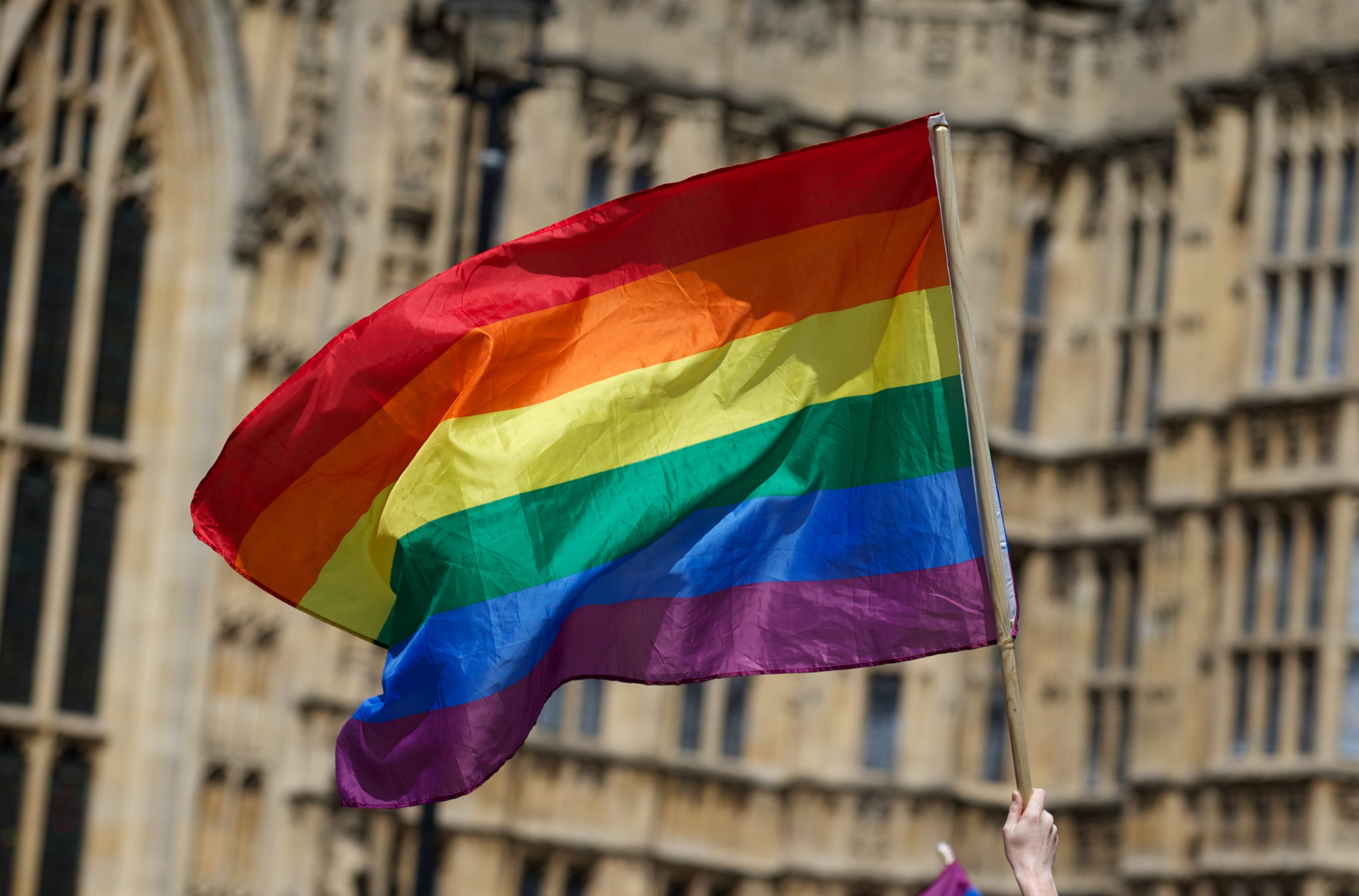 File: A gay campaigner waves the rainbow flag during a rally outside the houses of parliament