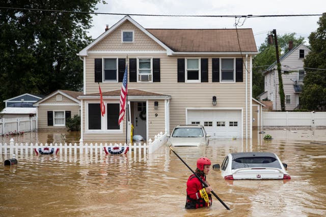 <p>A New Market Volunteer Fire Company rescue crew member wades through high waters following a flash flood, as Tropical Storm Henri makes landfall, in Helmetta, New Jersey, on 22 August 2021</p>
