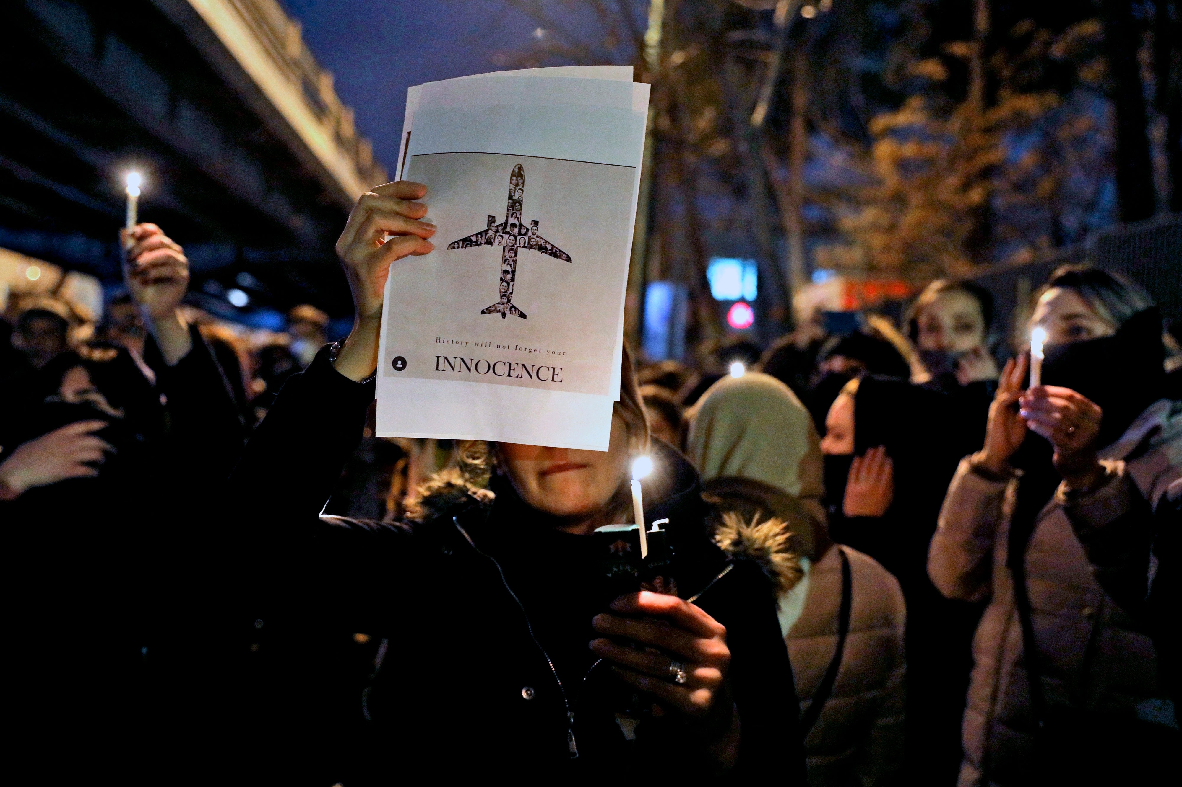 People gather for a candlelight vigil to remember the victims of a Ukraine plane crash