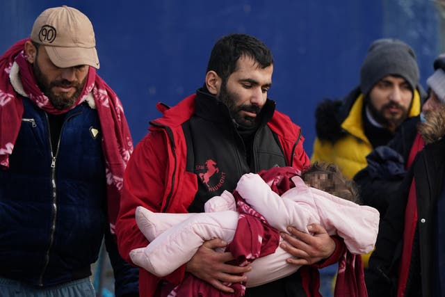 A man thought to be migrants carries a small child after they were brought in to Dover (Note: children’s faces have been pixelated) (PA)