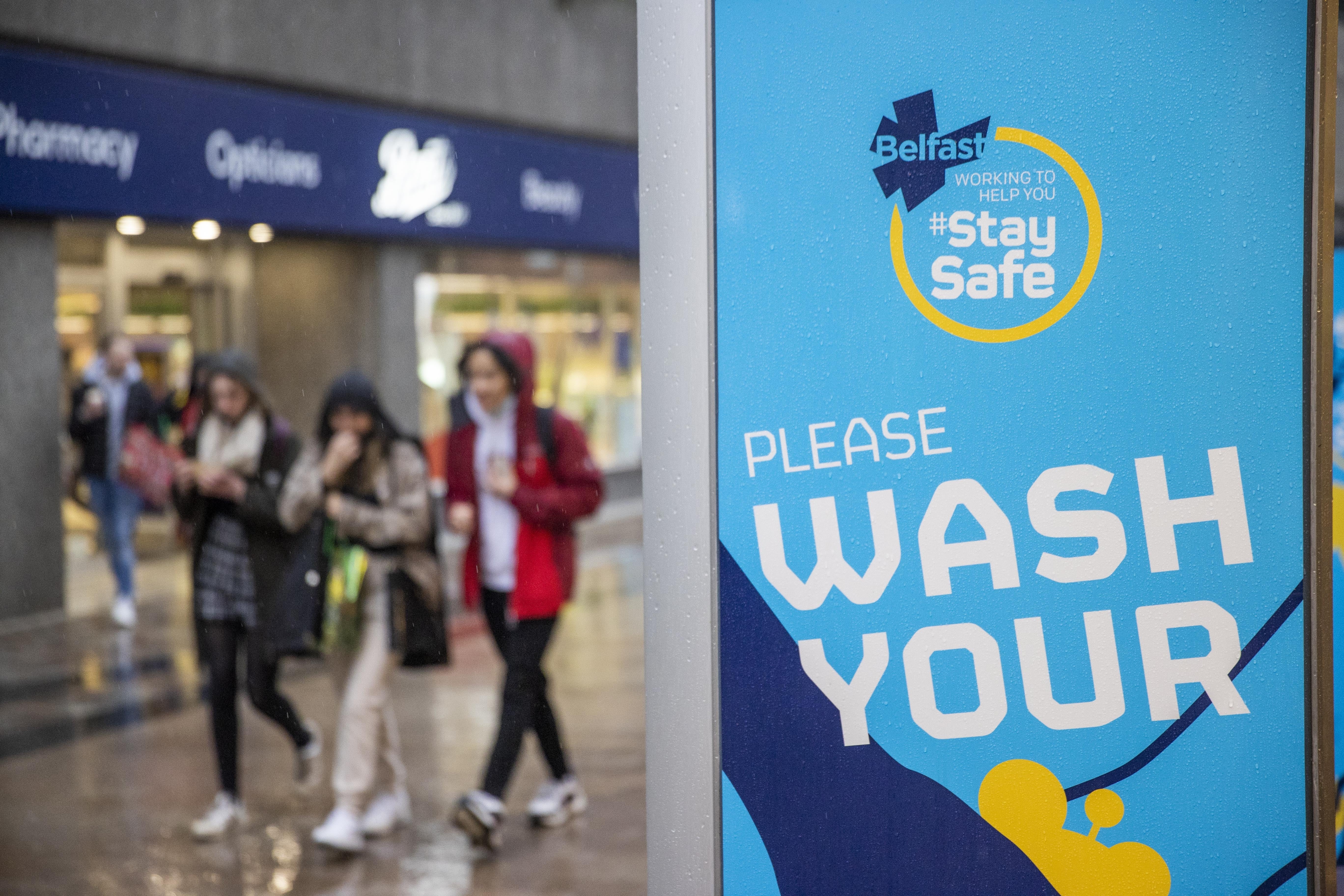 Young people walk past a Covid safety message from Belfast City Council (Liam McBurney/PA)