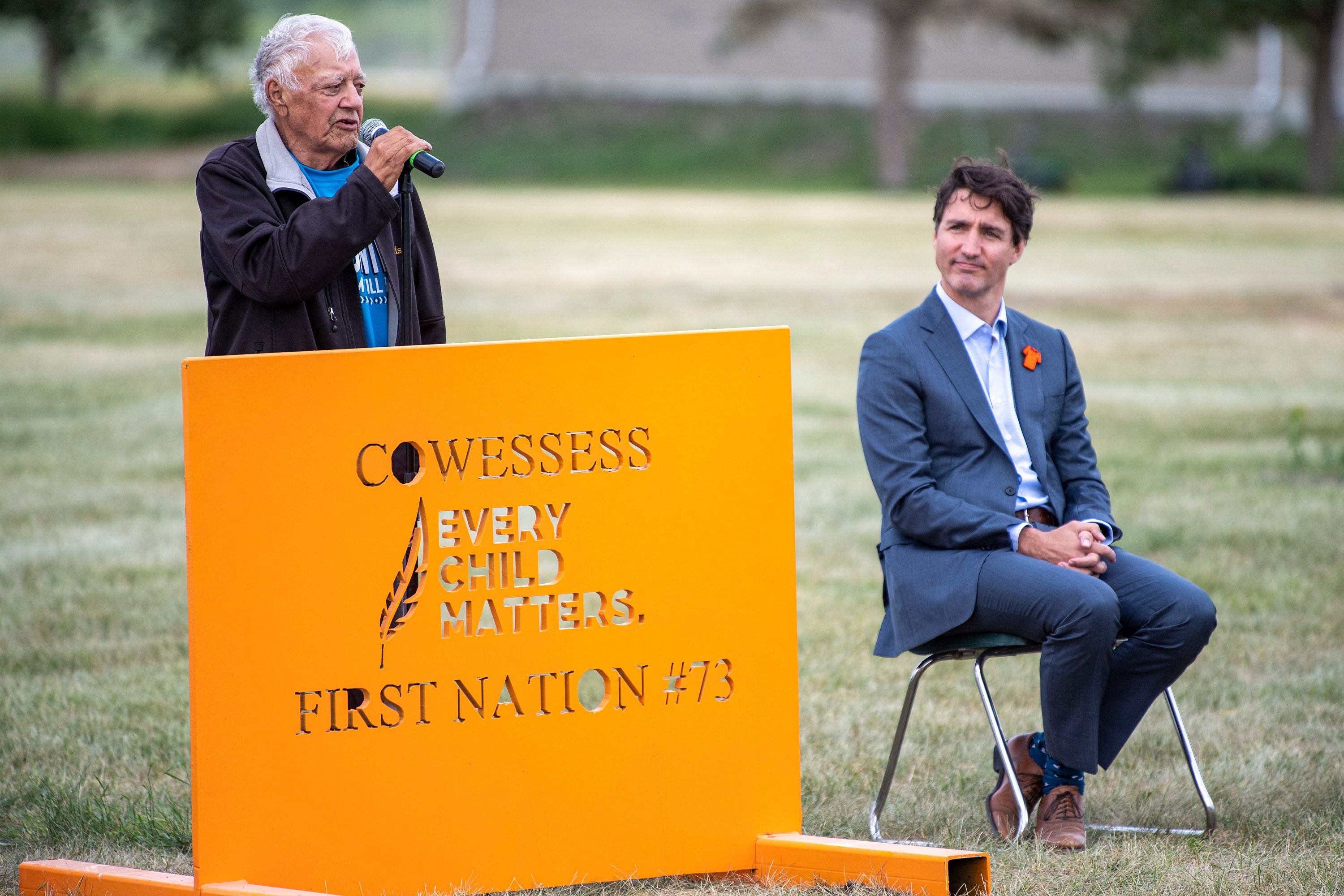 File: Prime Minister Justin Trudeau listens during a ceremony at the site of a former residential school where small flags are placed in spots of unmarked graves, in Cowessess First Nation, Sask
