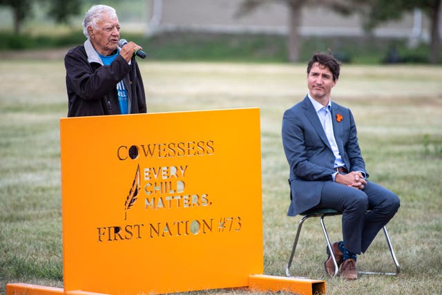 <p>File: Prime Minister Justin Trudeau listens during a ceremony at the site of a former residential school where small flags are placed in spots of unmarked graves, in Cowessess First Nation, Sask </p>
