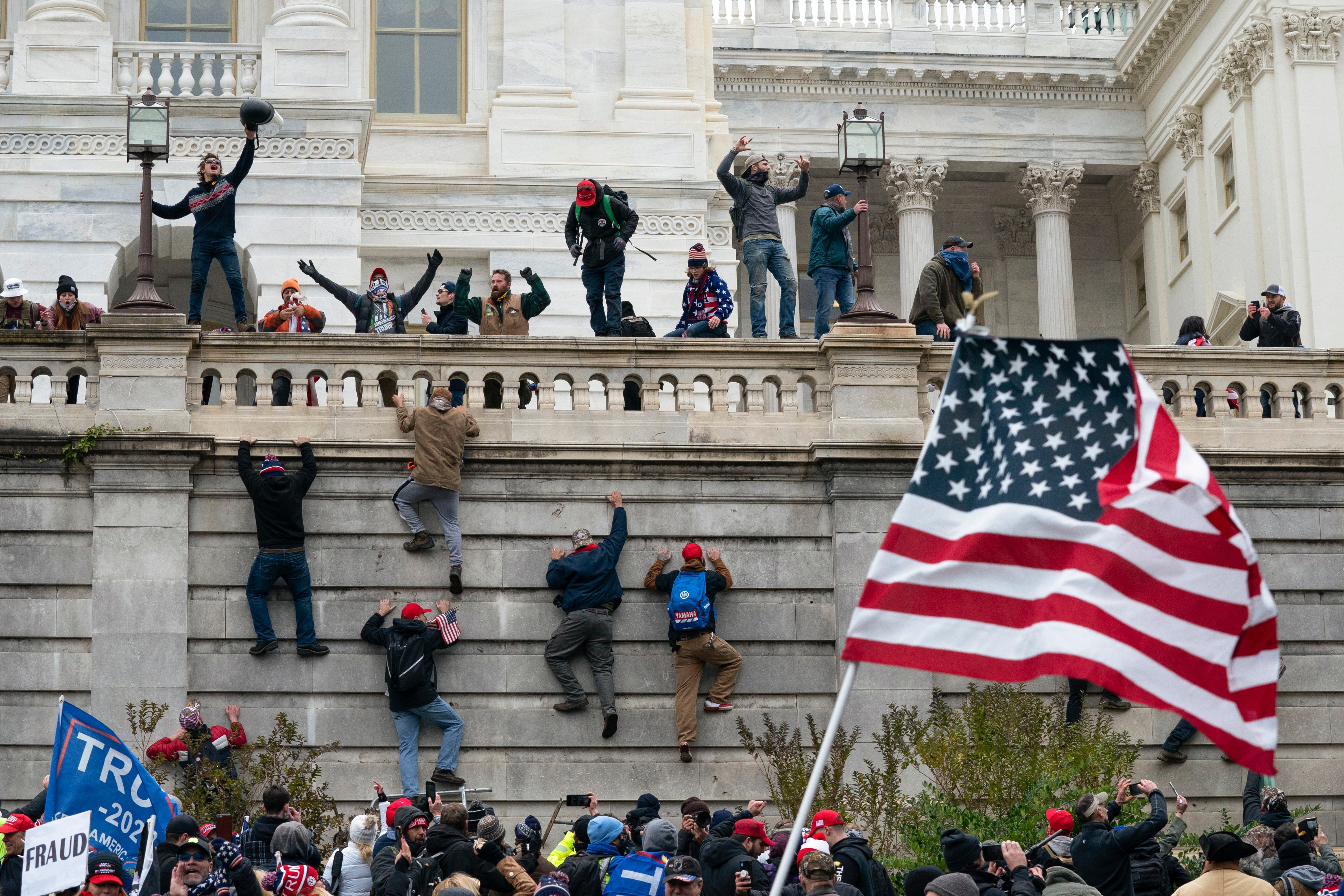Rioters scale a wall at the US Capitol