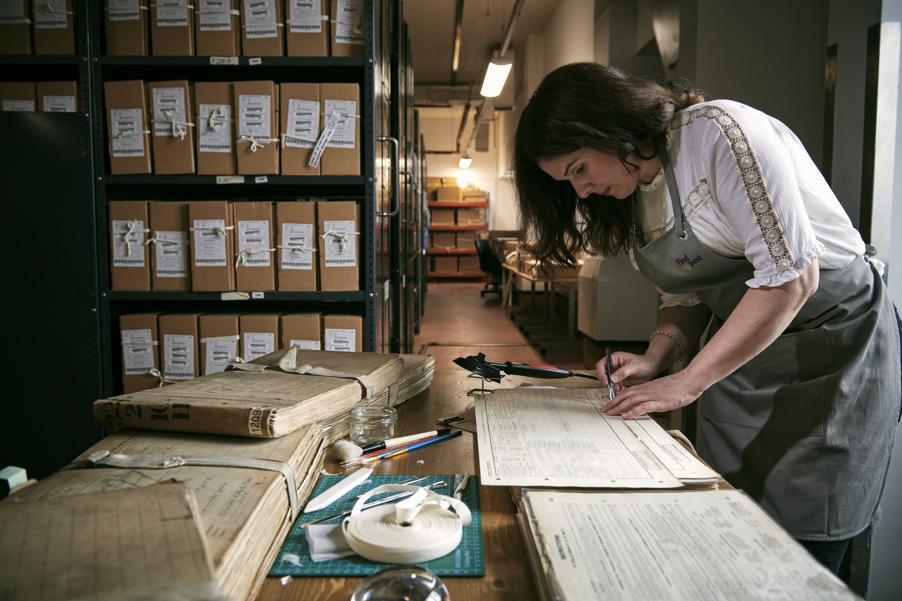 Rebecca Hayward, a Findmypast conservation technician, assessing damage to the pages of one of the 30,000 volumes of the 1921 census (Mikael Buck/Findmypast/PA)
