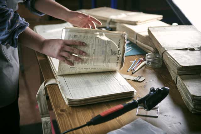 Emily Briffet, a Findmypast conservation technician, repairing damage to a page of one of the 30,000 volumes of the 1921 Census at the Office for National Statistics (ONS) near Southampton (FindMyPast/PA)