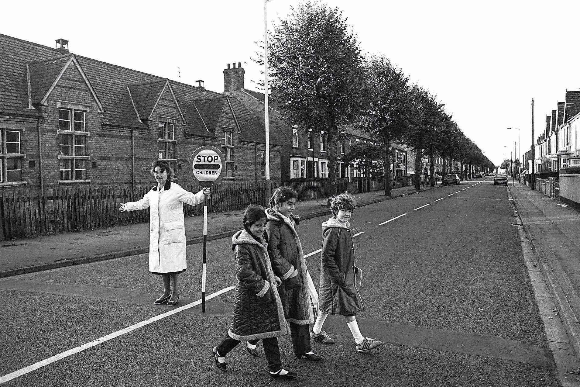 Lollipop lady Gloria Steele and schoolgirls Mazia Ahmad, Gulfraz Umar and Tanya Porter crossing the road in the 1980s