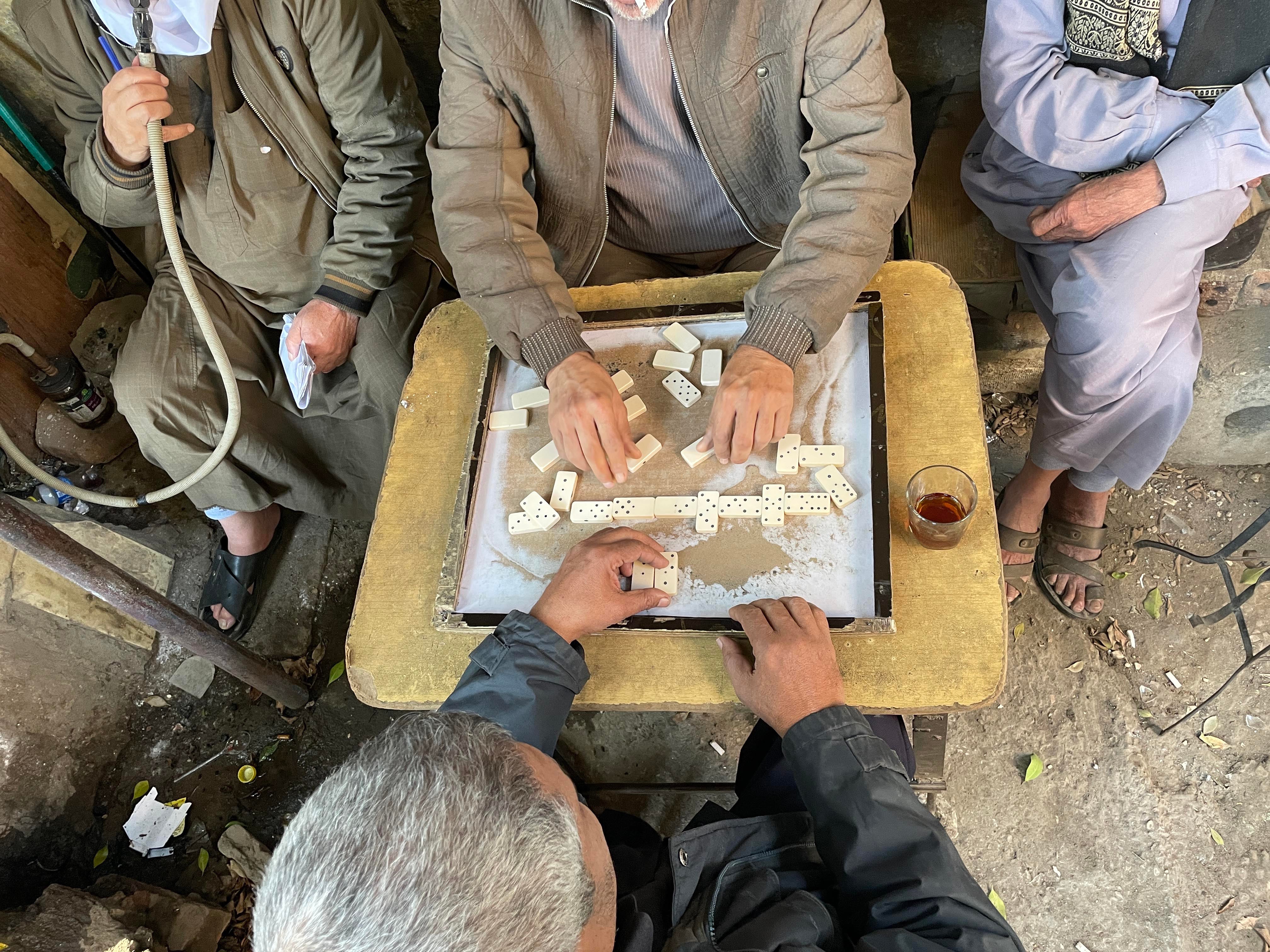 Men play dominoes and smoke shisha at an ahwa