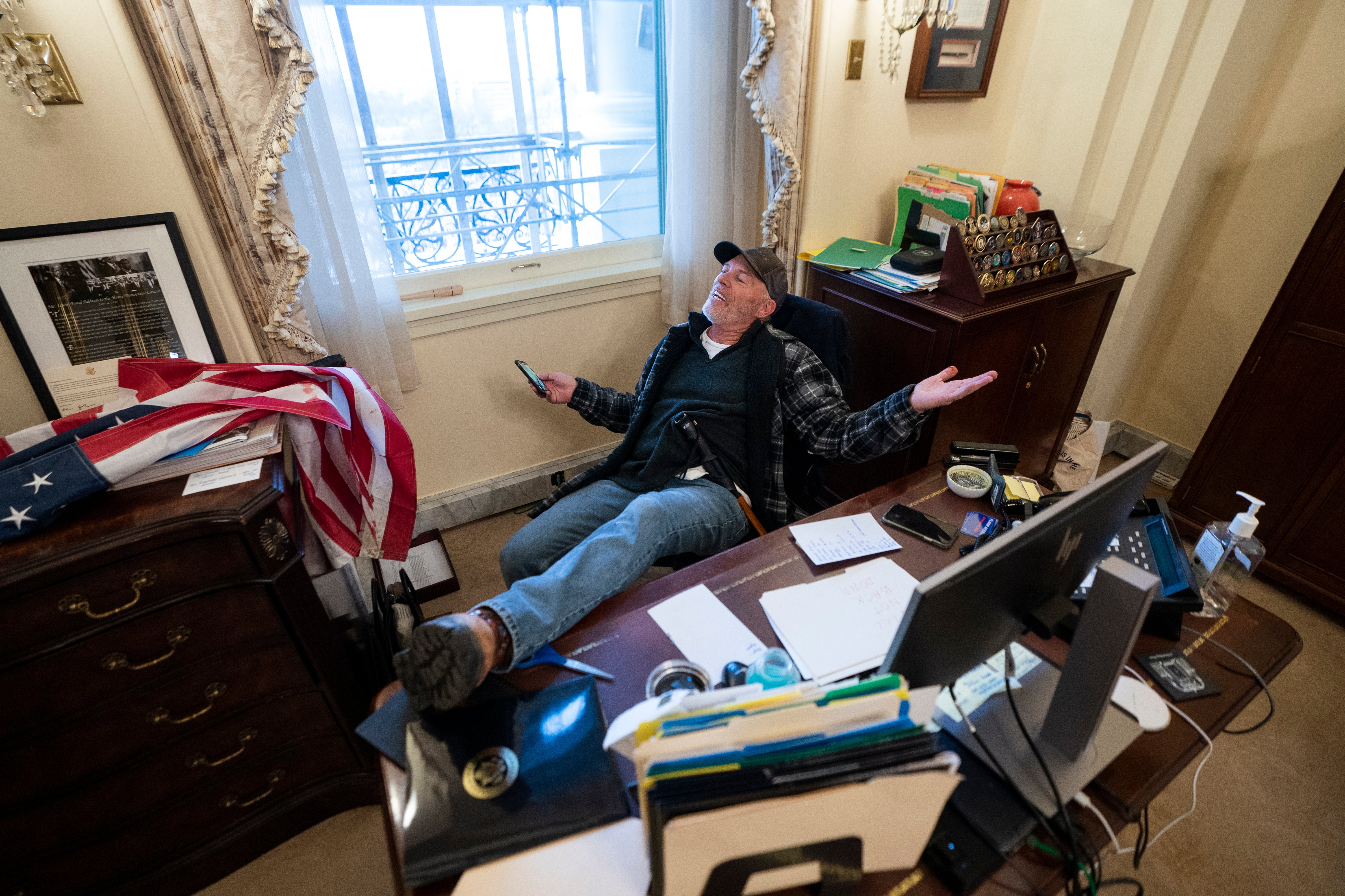 A supporter of US President Trump sits on the desk of US House Speaker Pelosi, after Trump supporters breached the US Capitol security in Washington, DC, on 6 January 2021