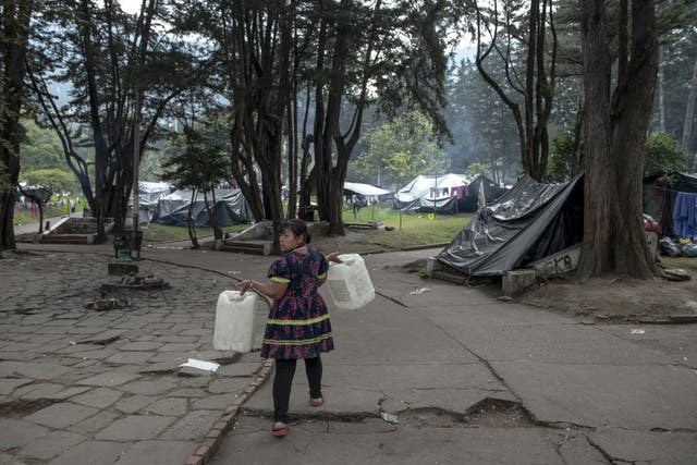 <p>Maria Lubia Queracama Tanigama carries two cans to fill at the spring that provides water for the protest camp in National Park in the centre of Bogota </p>
