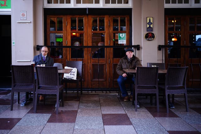 Two men sit socially distanced outside a pub in the centre of Cardiff (Ben Birchall/PA)