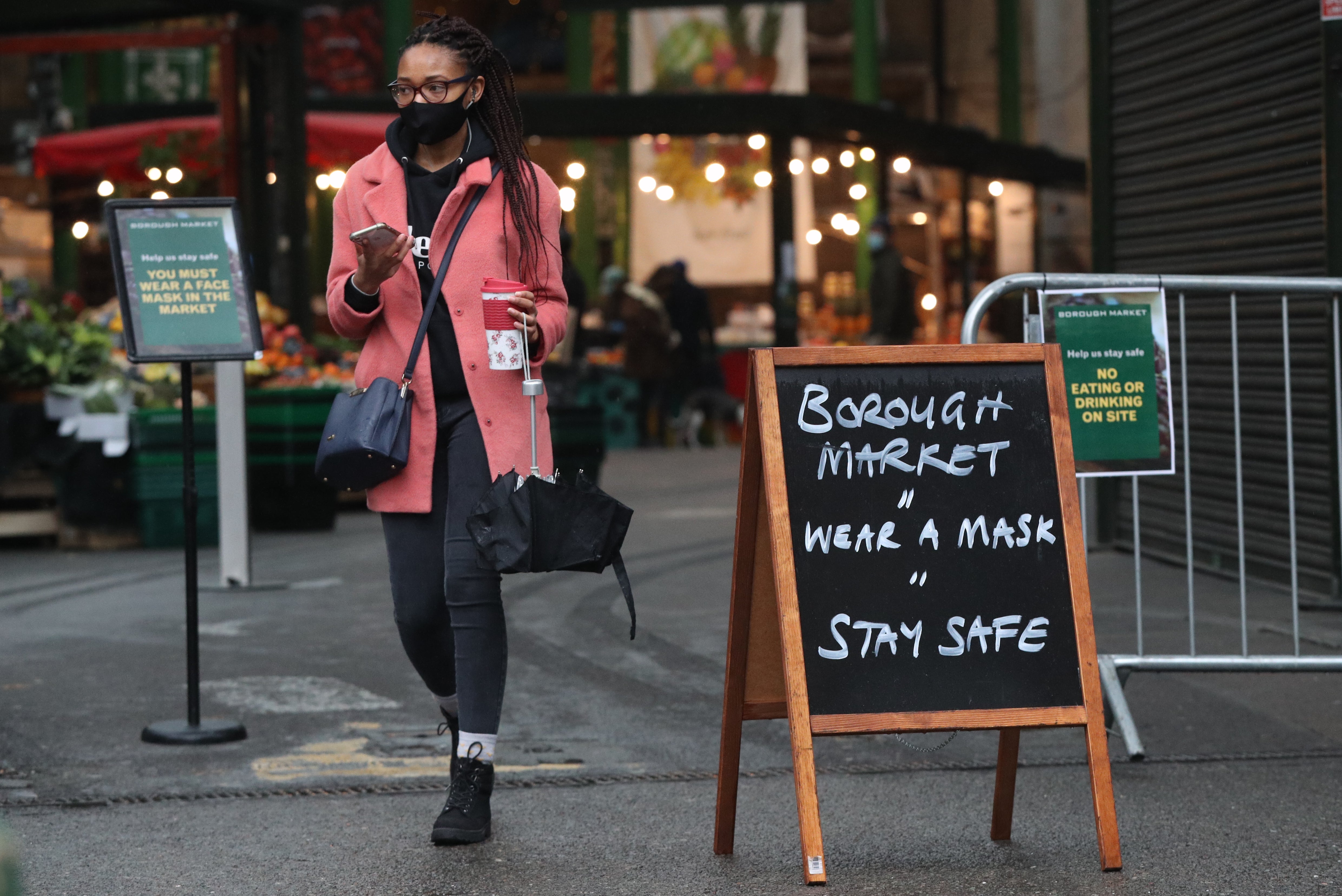 A shopper passes a coronavirus advice sign at Borough Market, London, which has become the first outdoor space in the UK to legally enforce the wearing of face masks (Jonathan Brady/PA)