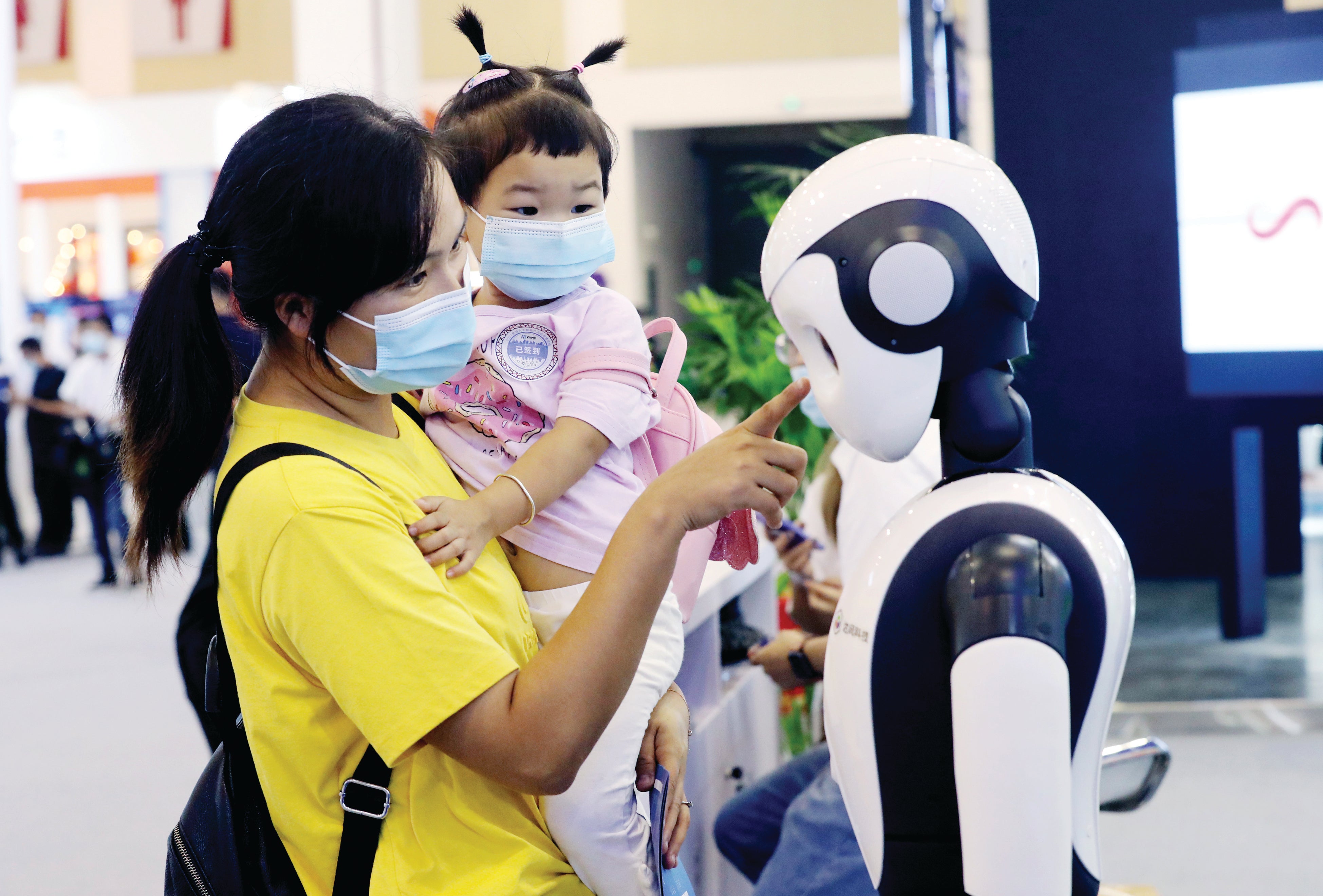 A mother and her daughter interact with an intelligent robot at an industrial expo in Suzhou, Jiangsu province, in September 2021
