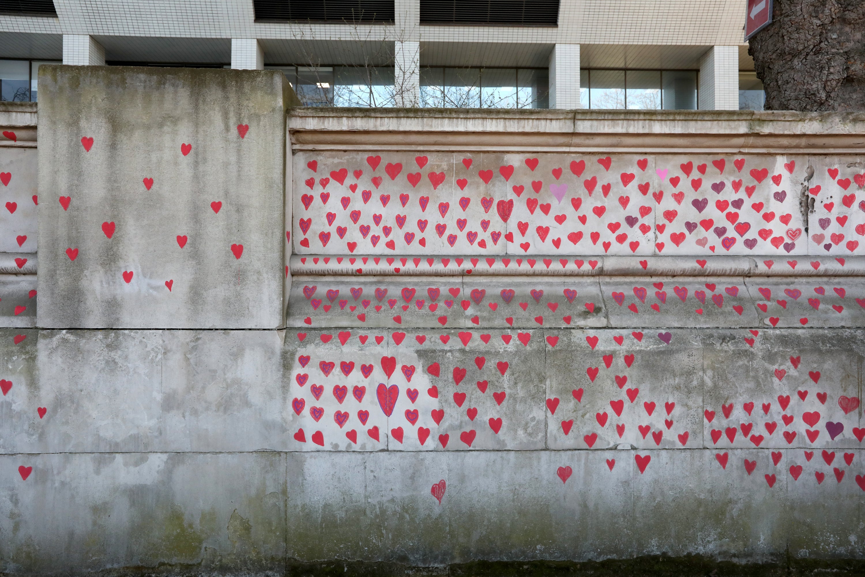 Red hearts painted by members of bereaved families on the COVID-19 Memorial Wall opposite the Houses of Parliament at Embankment, central London (Lucianna Guerra/PA)