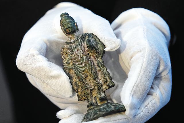 <p>An archaeologist displays the standing statuette of the Gautama Buddha discovered in Xianyang, Shaanxi province</p>