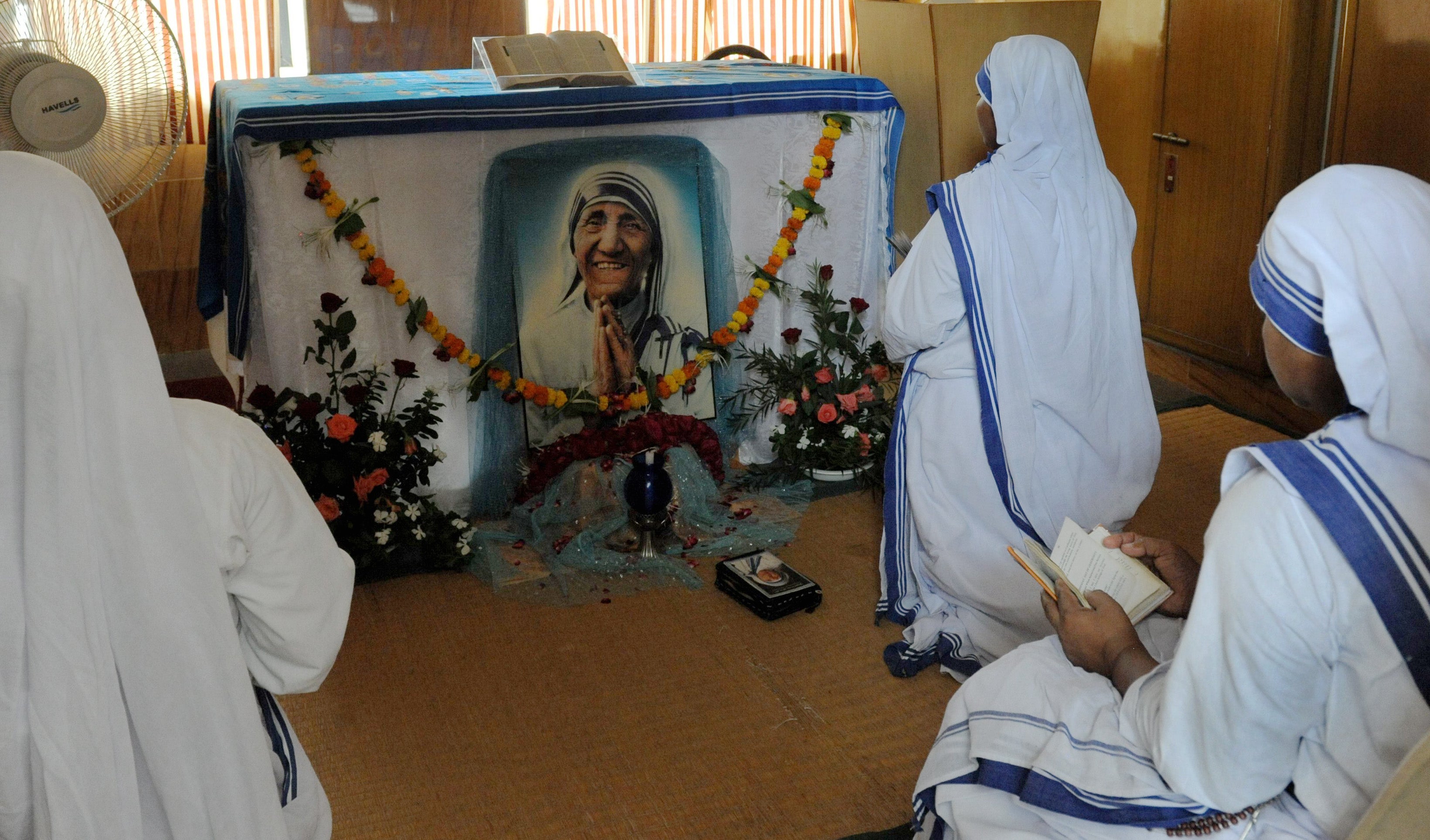 Christian nuns pray in front of a photograph of Mother Teresa as they observe the fifteenth anniversary of her death