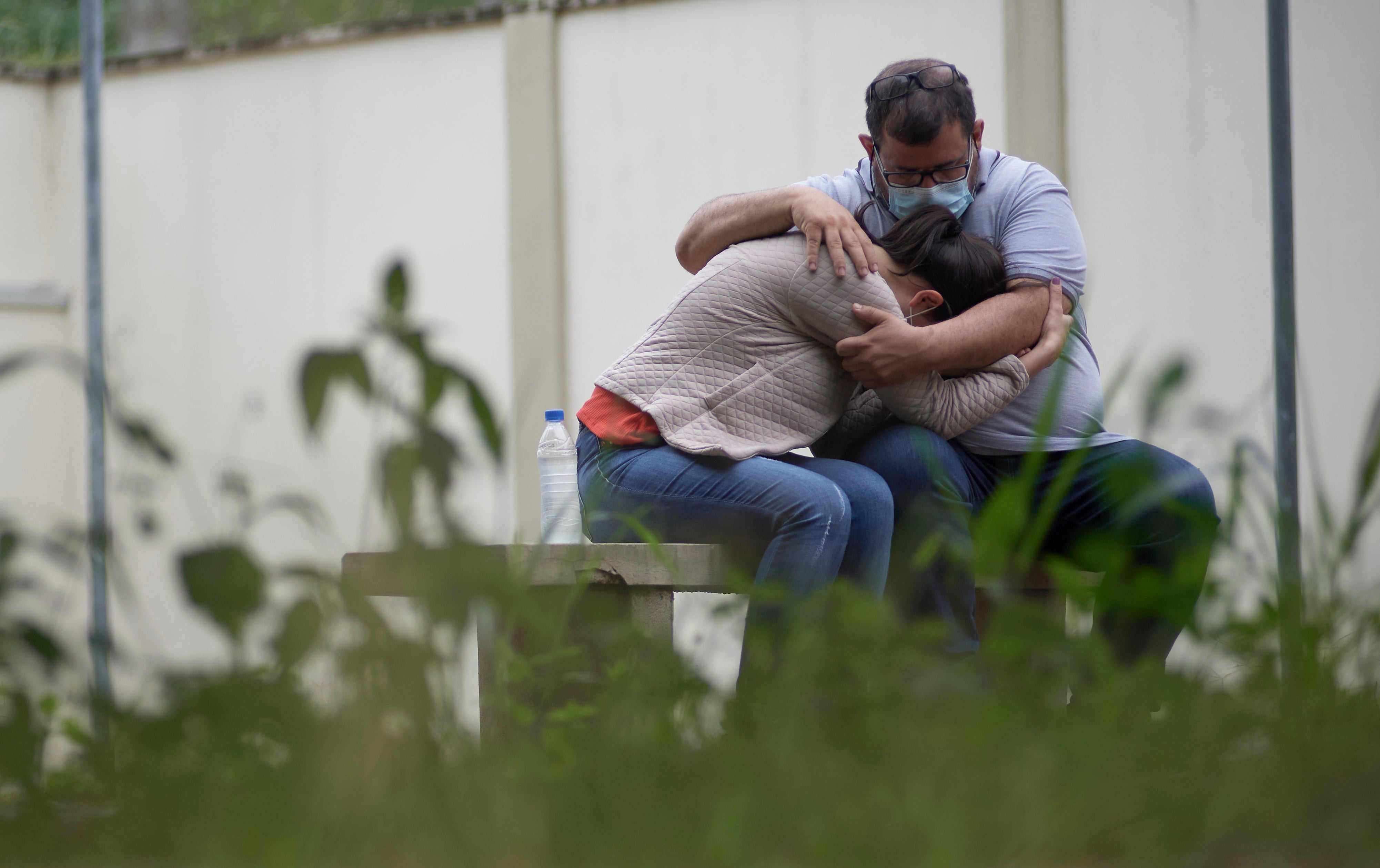 A couple embraces as they wait for information about missing relatives after a massive slab of rock broke away from a cliff