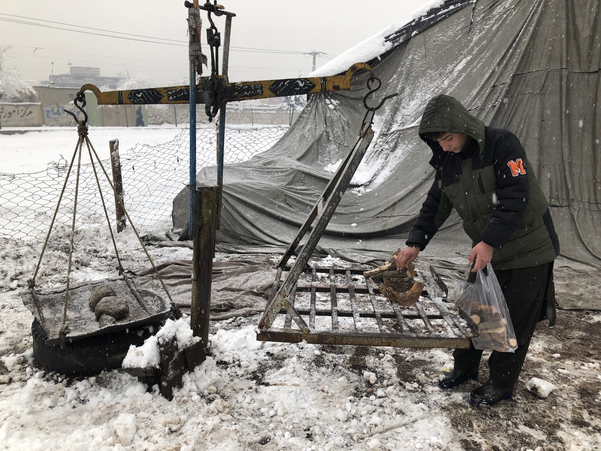 A few sticks of firewood, weighed on a scale and sold for half a dollar, are all that the family of this boy and many others can afford to heat their homes in Kabul