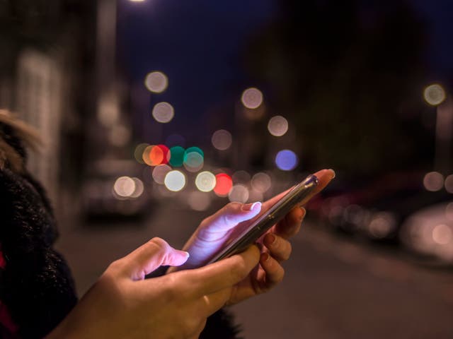 <p>A woman uses her phone while travelling at night</p>