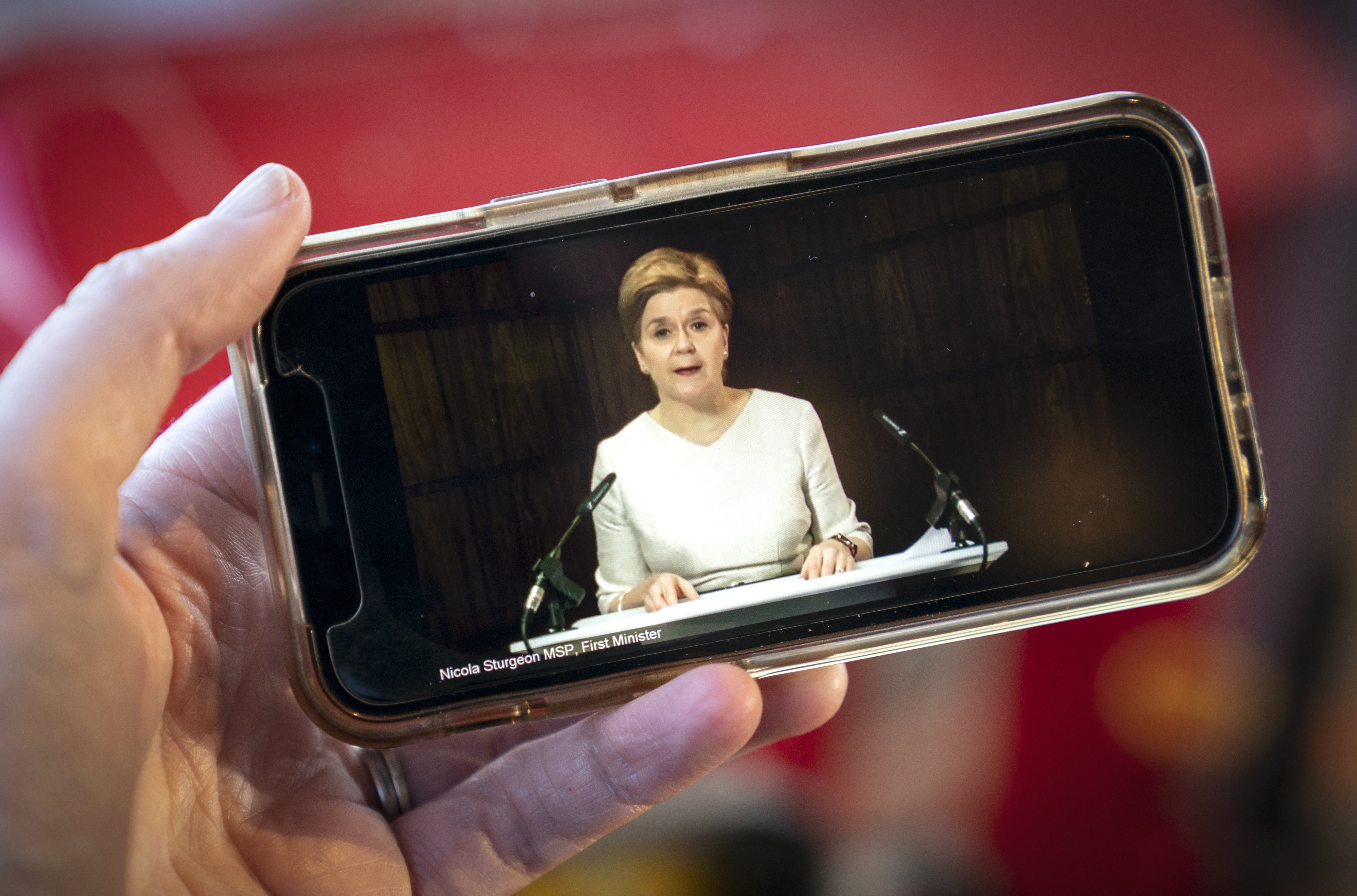 First Minister Nicola Sturgeon delivering an update statement is streamed on a smartphone during a virtual session of the Scottish Parliament (PA)