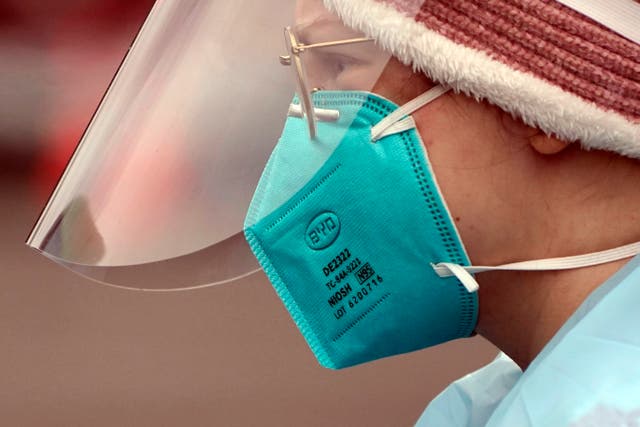 <p>A medical assistant working at a drive-up COVID-19 testing clinic in Washington state wears an N95 mask</p>