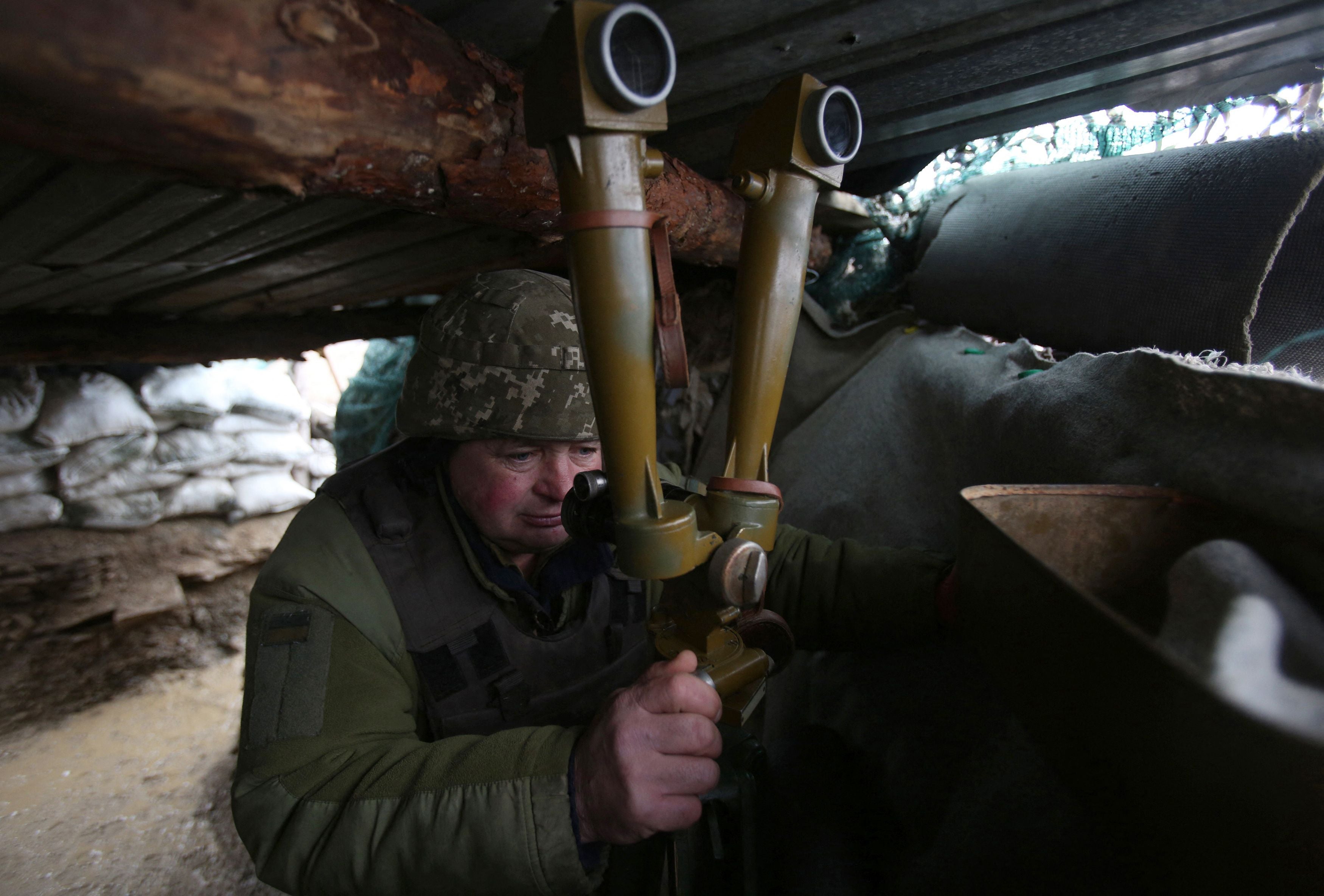 A Ukrainian serviceman watches through a spyglass in a trench on the frontline with Russia-backed separatists near Lugansk village, Donetsk