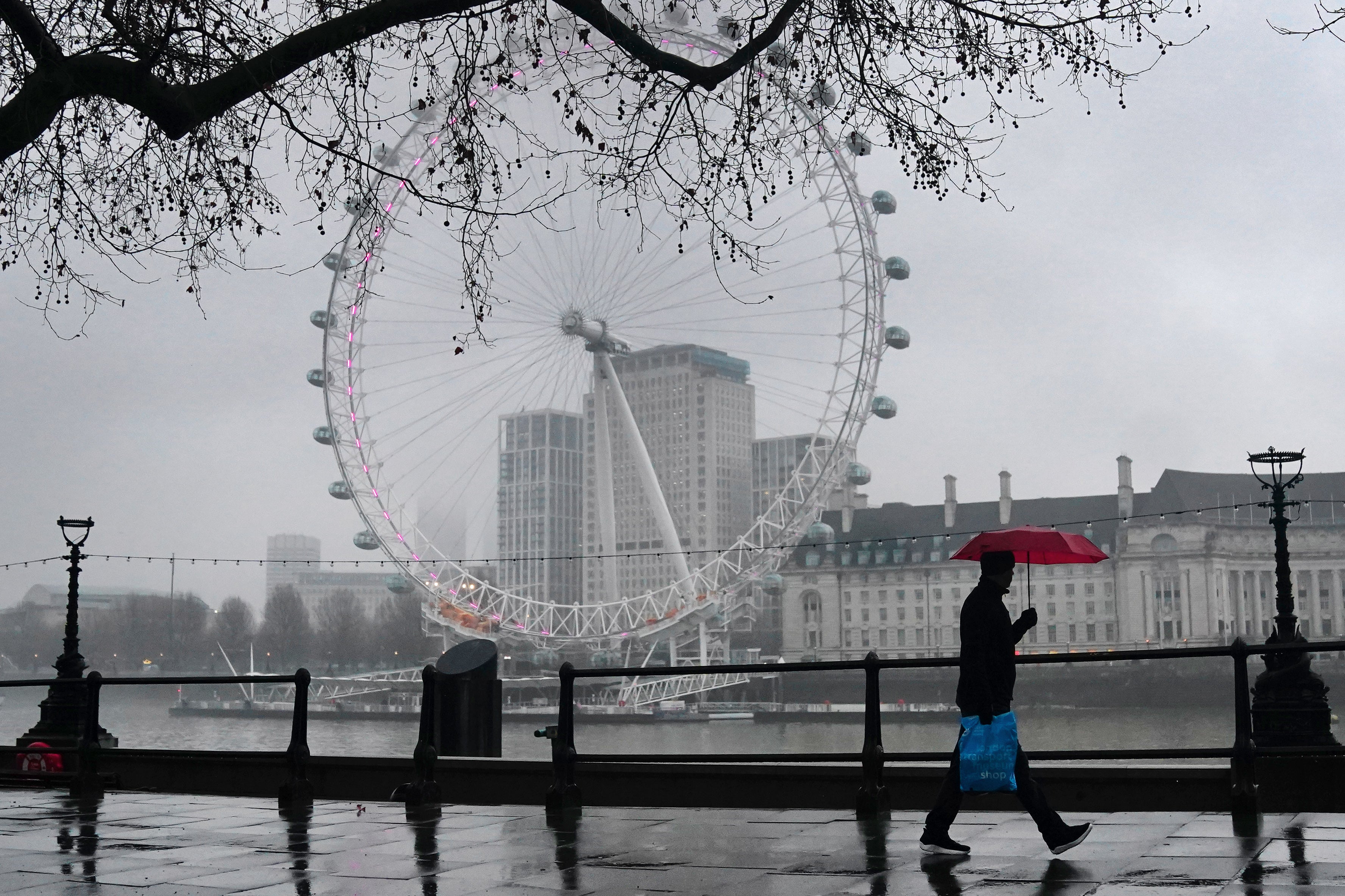 A man walks with an umbrella during wet weather on the Embankment in Westminster, on Tuesday 11 January 2022