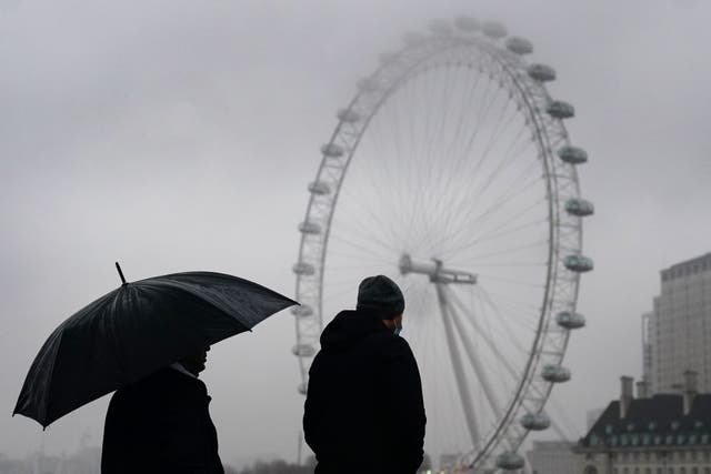 A couple walk underneath an umbrella during wet weather on Westminster Bridge in central London