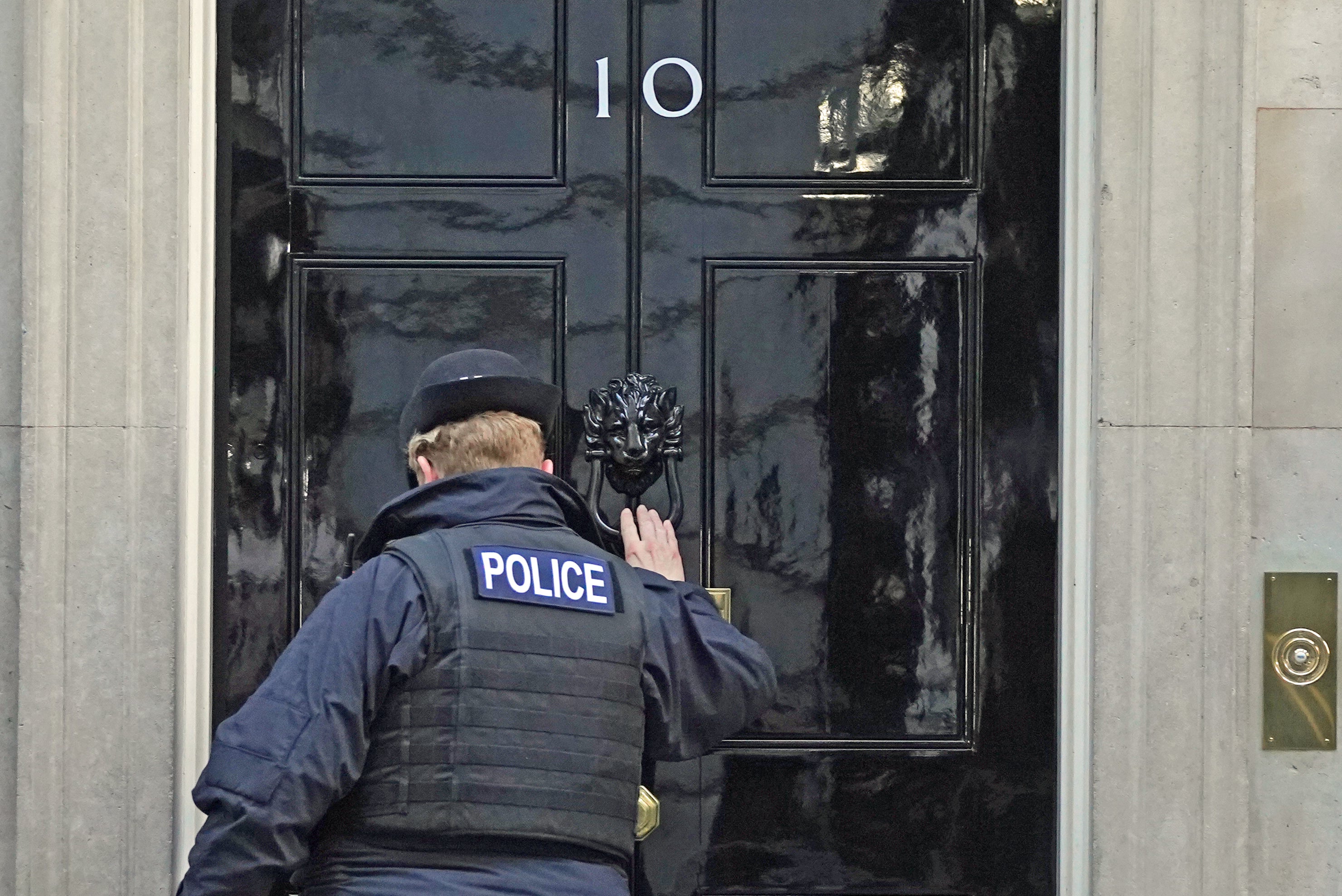 A police officer knocks on the door of the Prime Minister’s official residence in Downing Street, as public anger continues following the leak on Monday of an email from Boris Johnson’s principal private secretary, Martin Reynolds, inviting 100 Downing Street staff to a “bring your own booze” party on May 20, 2020 (Stefan Roussea/PA)