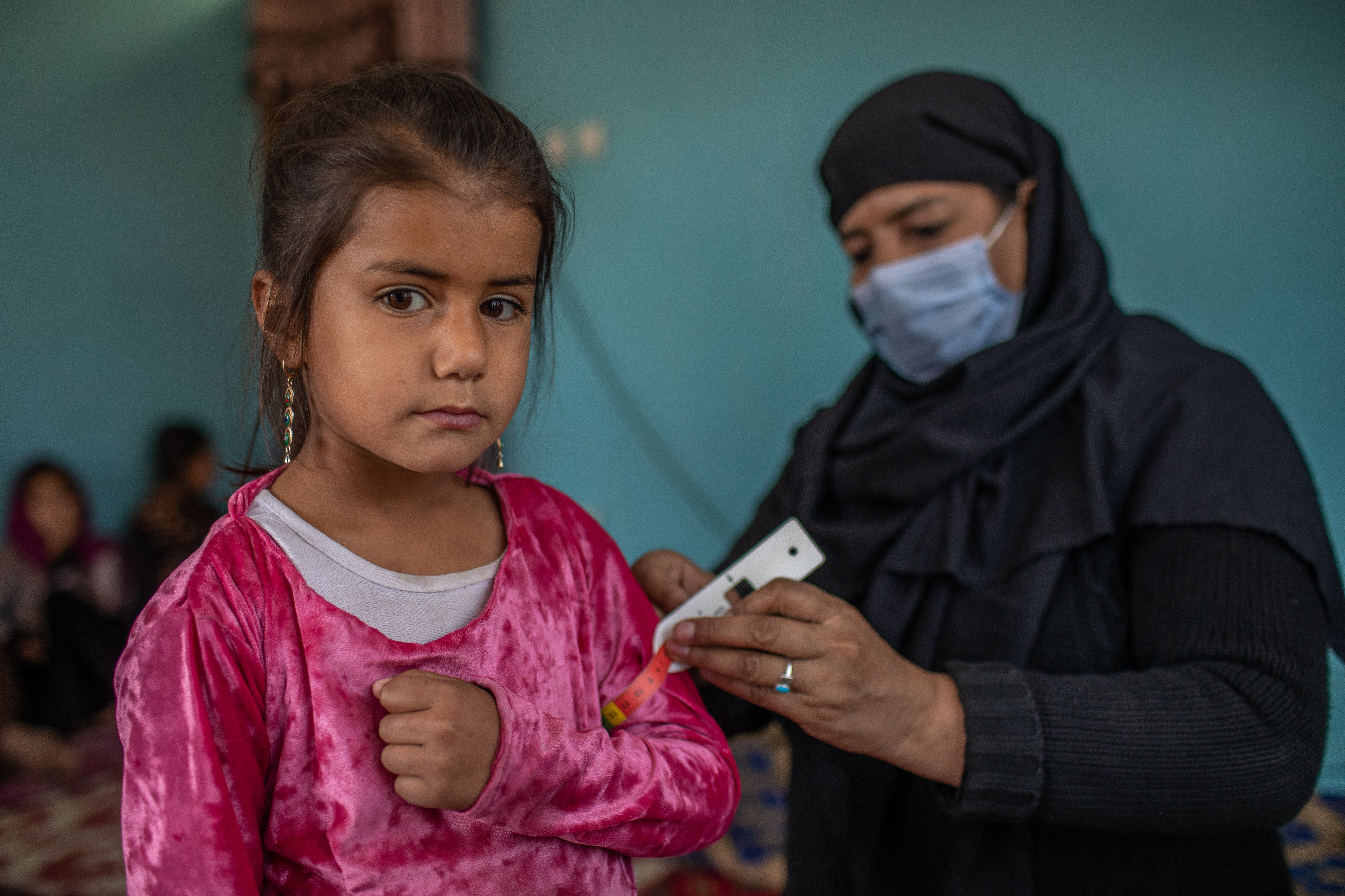 A child is examined by Nazo, an International Rescue Committee community health volunteer who goes door to door to visit mothers living within her community to educate them about how to prevent children becoming malnourished and contracting other diseases