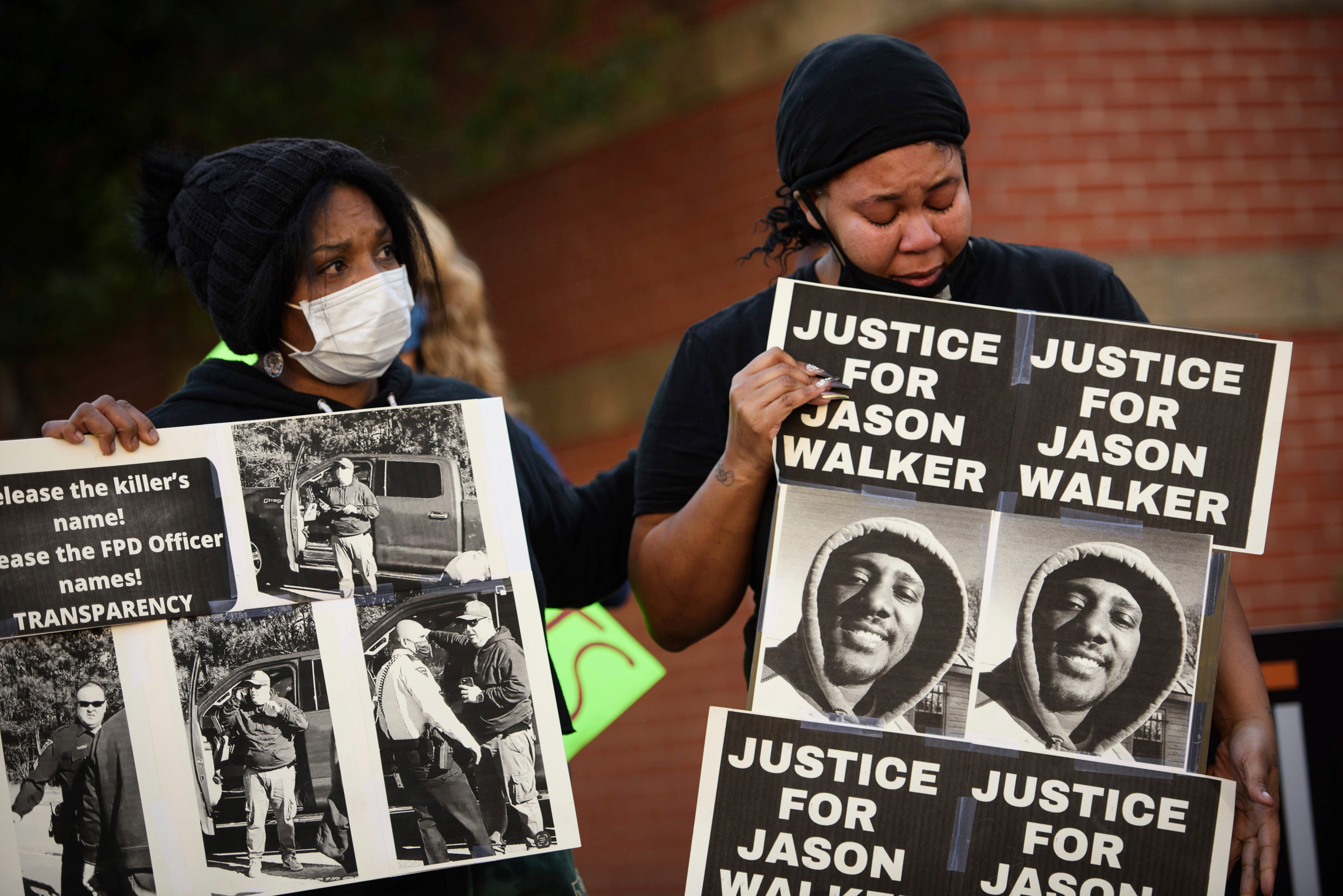 Protesters hold signs with a photo of Jason Walker during a demonstration in front of the Fayetteville Police Department on Sunday