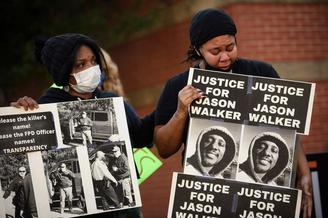 <p>Manifestantes sostienen carteles con una foto de Jason Walker durante una protesta frente al Departamento de Policía de Fayetteville el domingo </p>