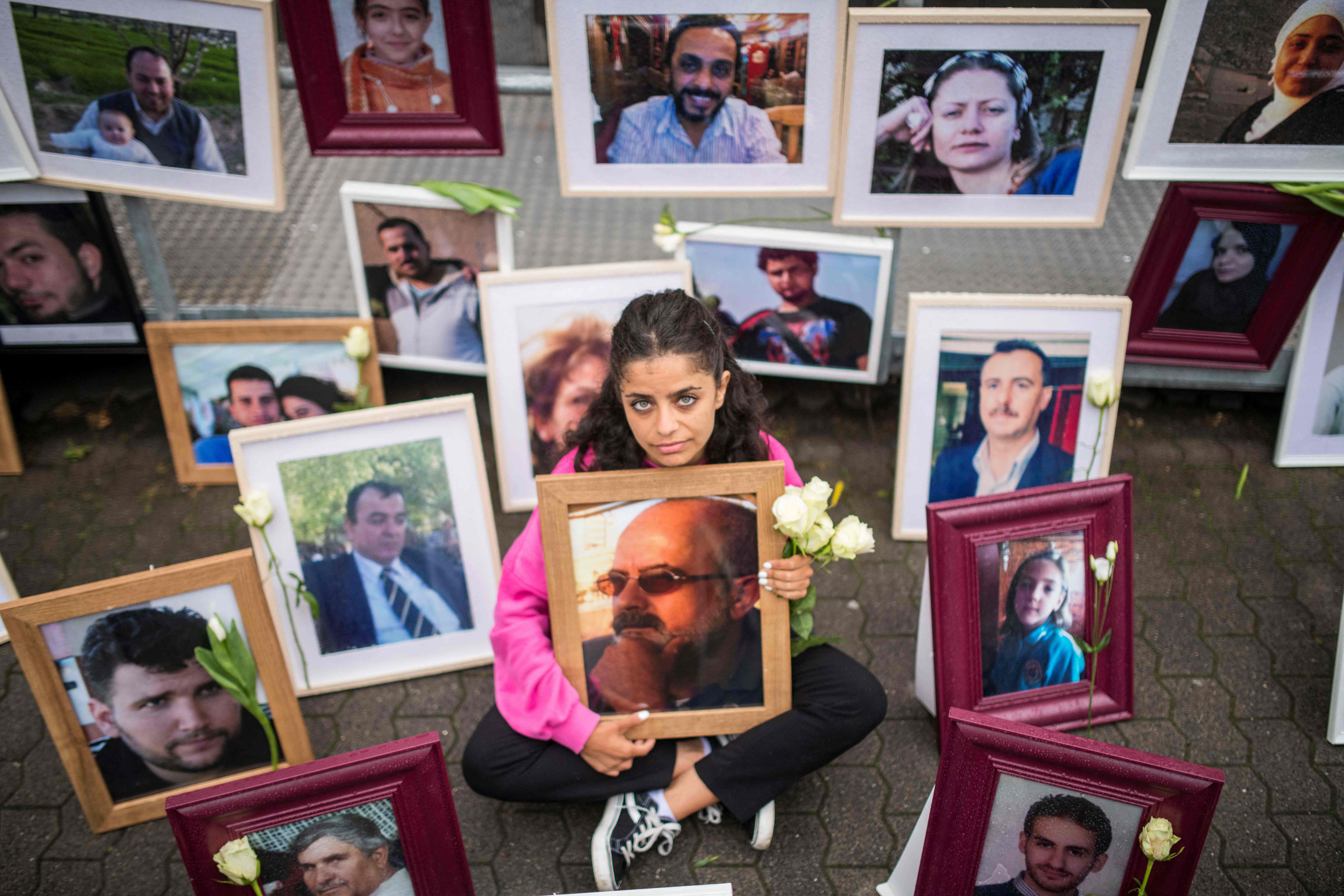 File photo: Syrian campaigner Wafa Mustafa sits between pictures of victims of the Syrian regime in Koblenz, western Germany, 4 June 2020