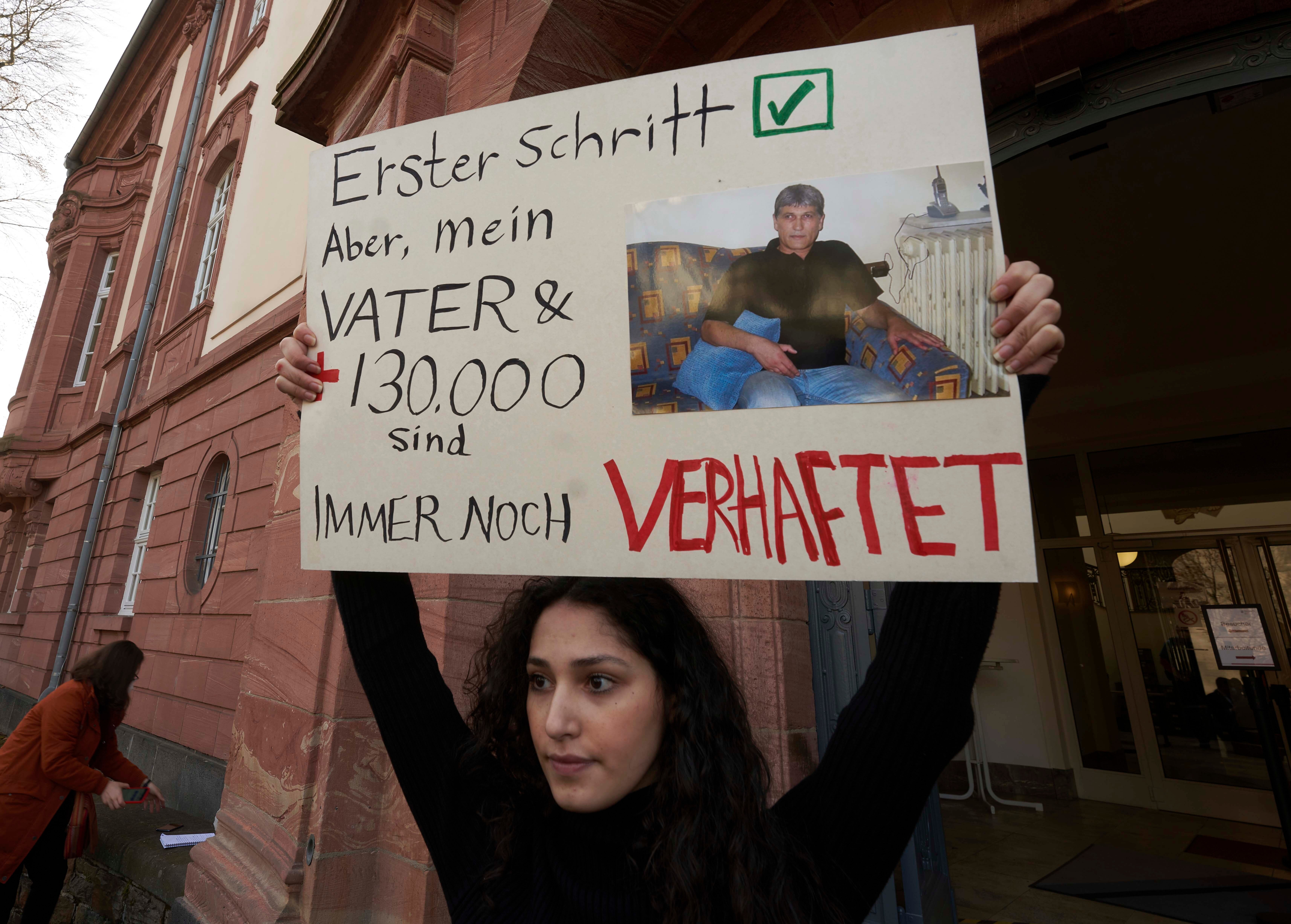 File photo: Serda Alshehabi holds a banner about her father’s detention in Syria in front of the court in Koblenz, Germany, 24 February 2021