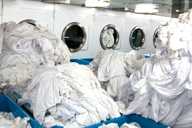 <p>Mountains of sheets about to go into drying machines. Up to 40 times more microscopic fragments were generated by dryers than washing machines, scientists found in tests</p>